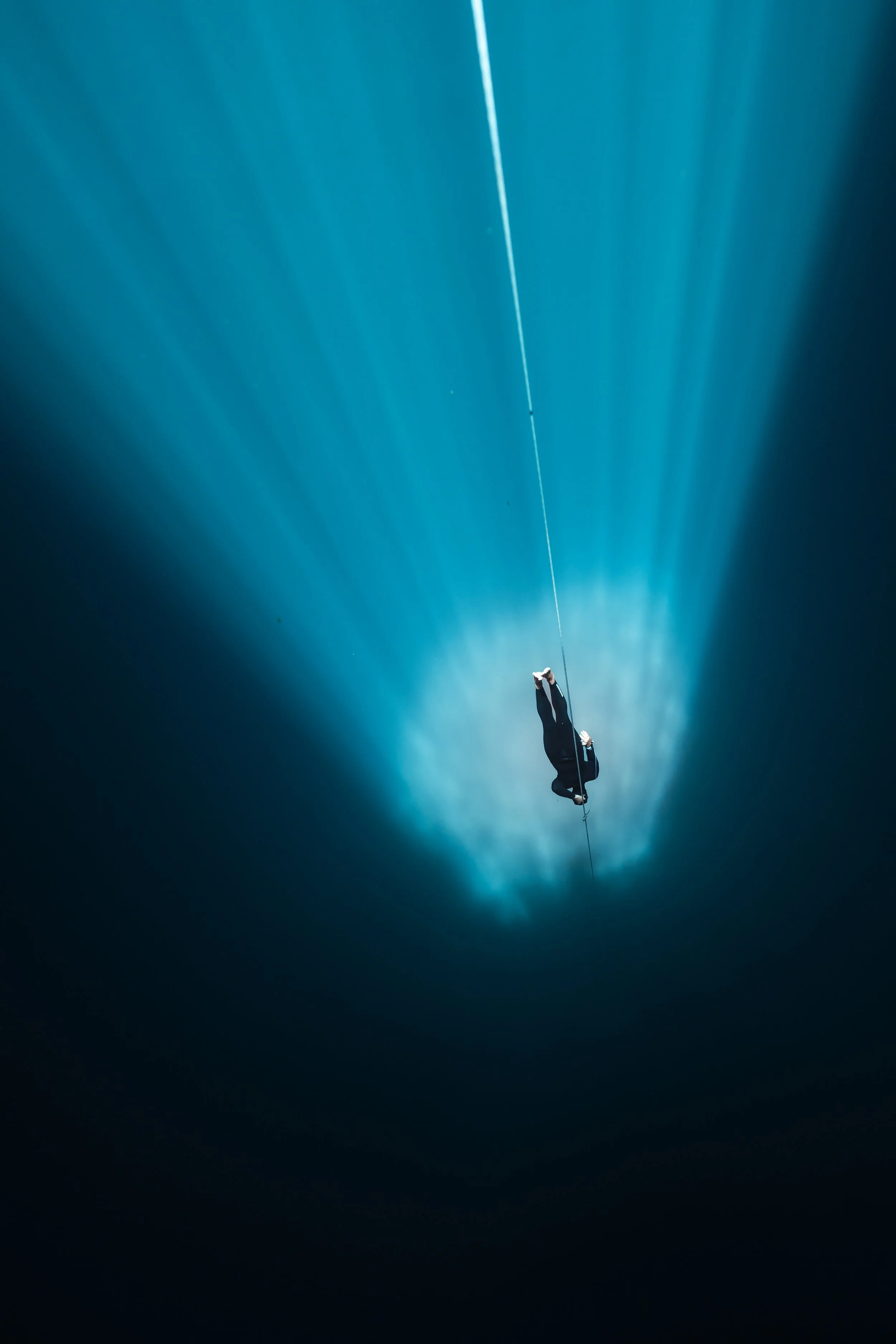 Thomas Dohm freediving deep on a line, passing through a sulphur cloud in a cenote in Tulum, Mexico. Photographed by Matthieu Duvault.