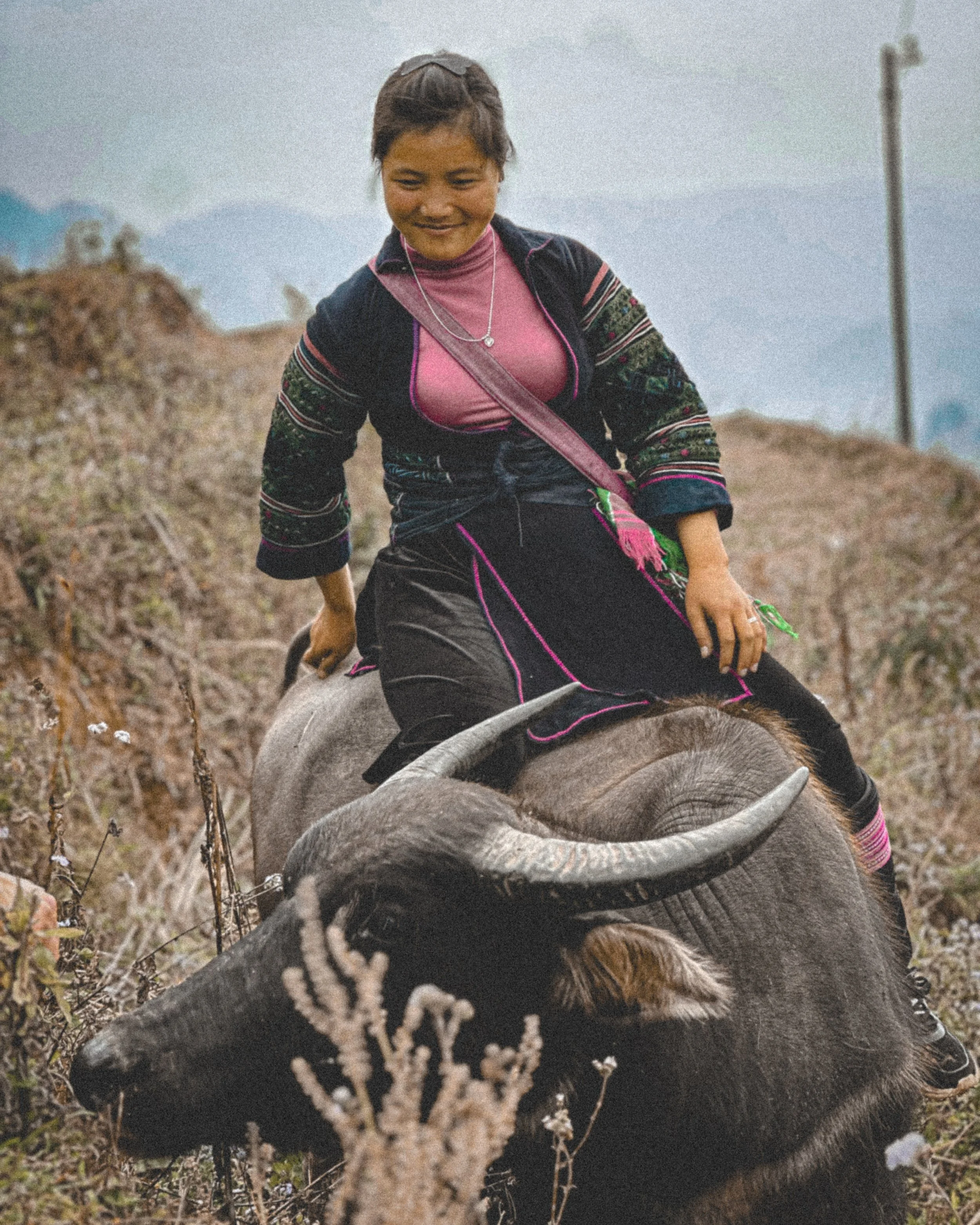 Hmong woman riding a water buffalo on a misty hillside near Sapa, northern Vietnam. Photography by Thomas Dohm.