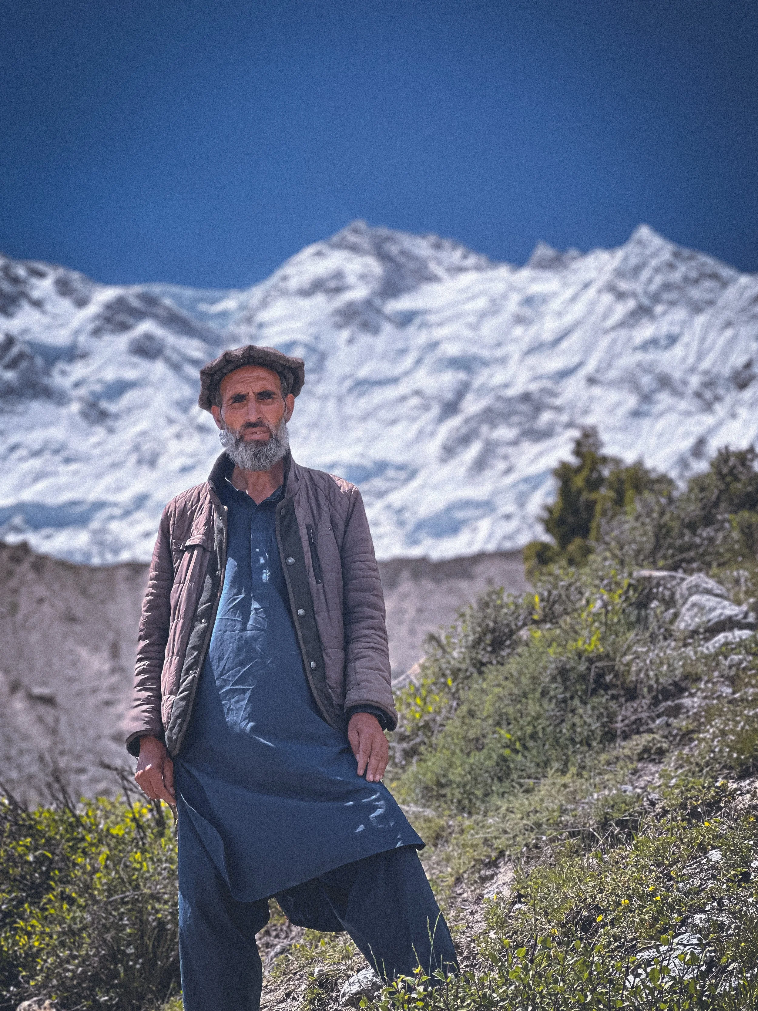Man in shalwar kameez standing against the Karakoram mountains in the Fairy Meadows, Pakistan. Photography by Thomas Dohm.