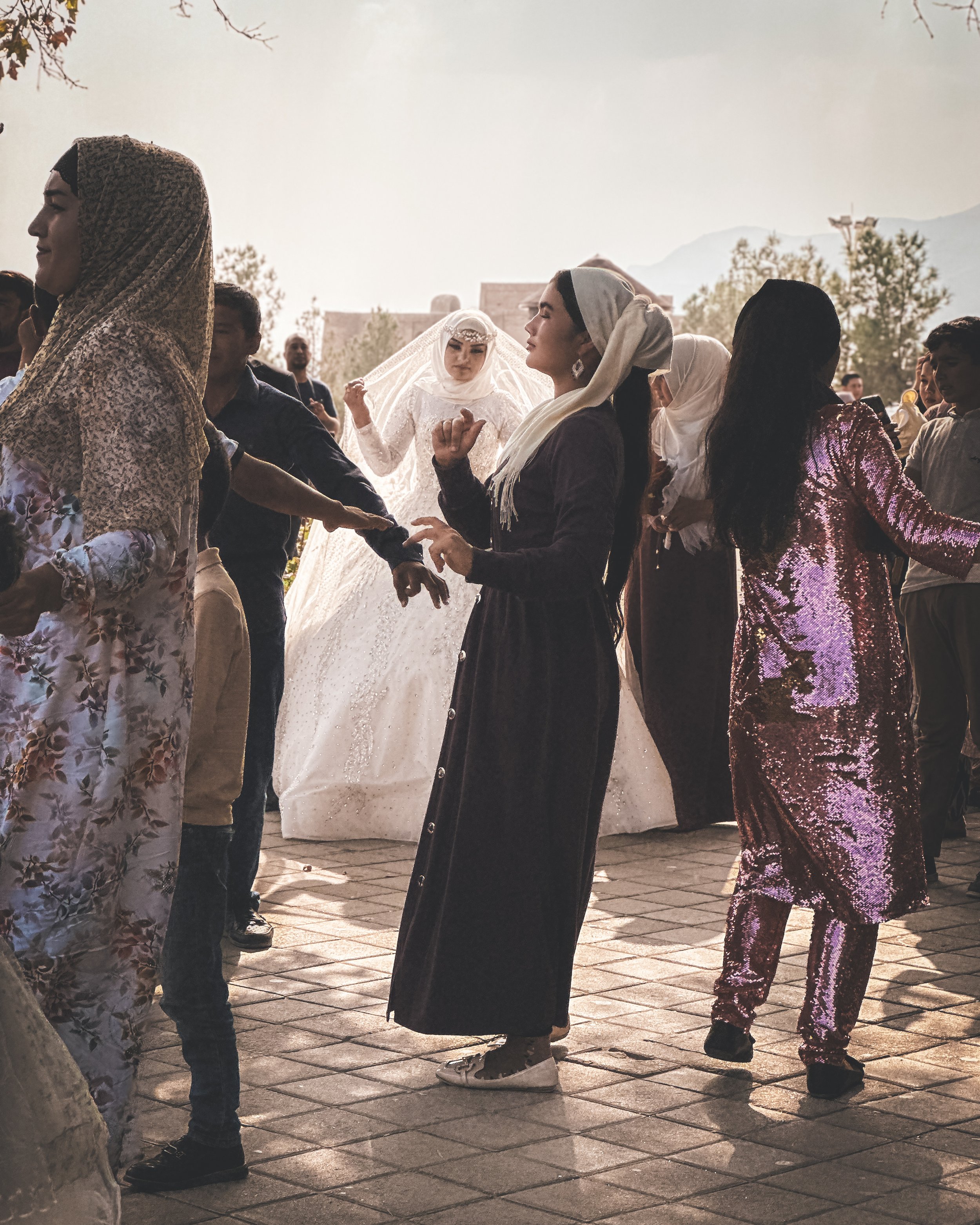 Bride glimpsed through colourful fabrics and guests at a wedding in Dushanbe, Tajikistan. Photography by Thomas Dohm.