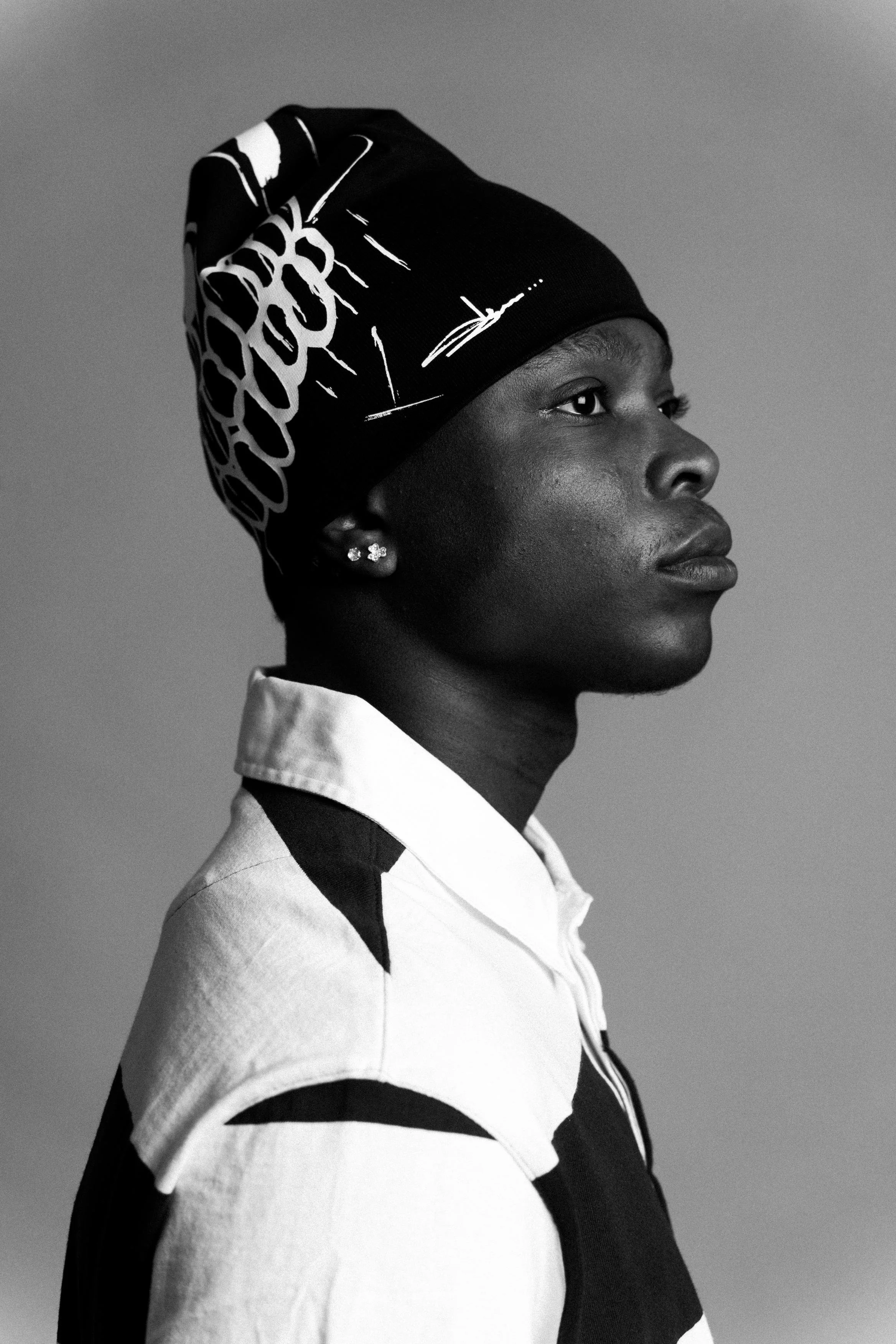 Black and white portrait of a woman in profile with a headscarf and earrings.