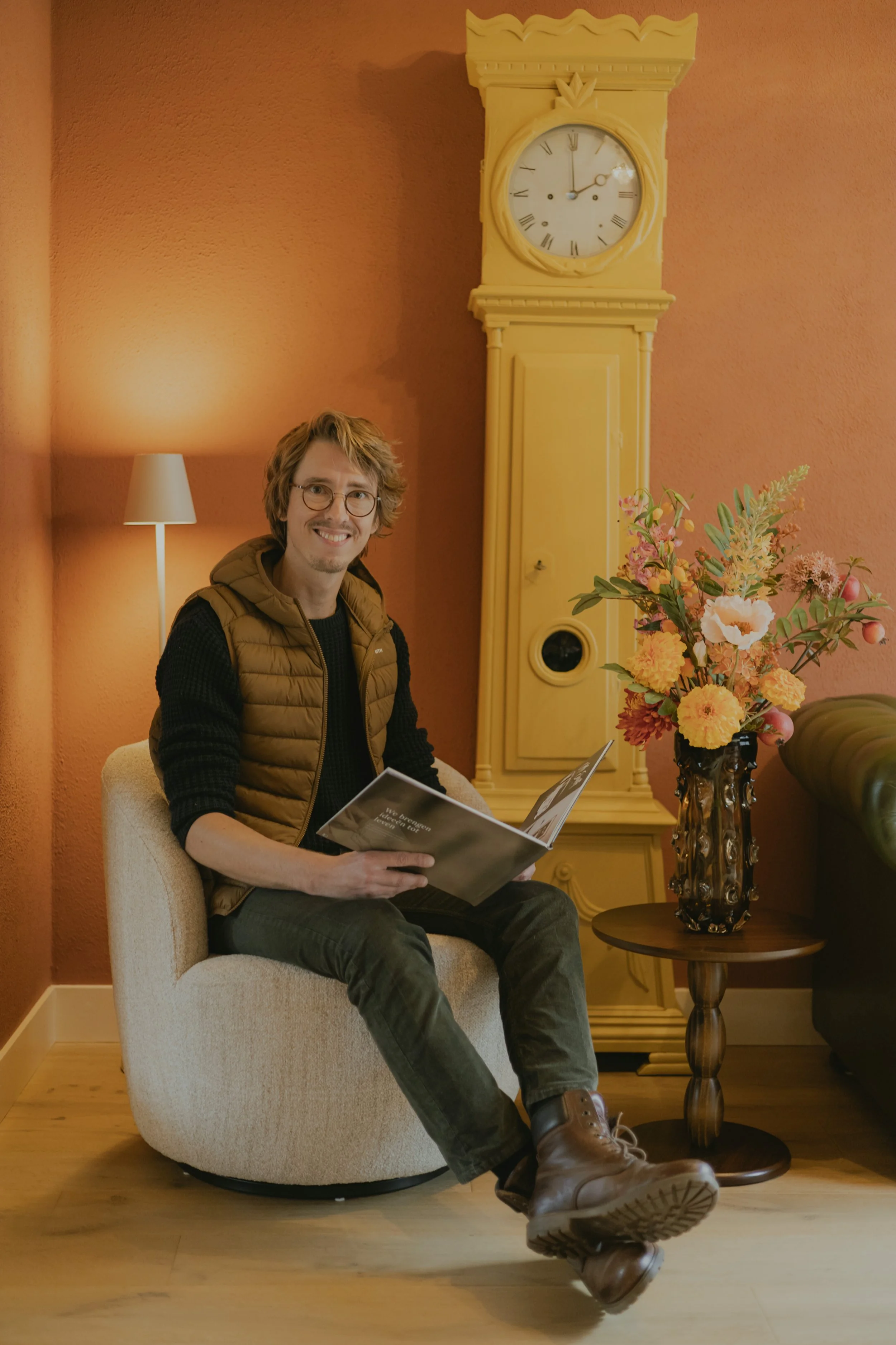 Persoon zittend in fauteuil leest een boek in warm en stijlvol interieur