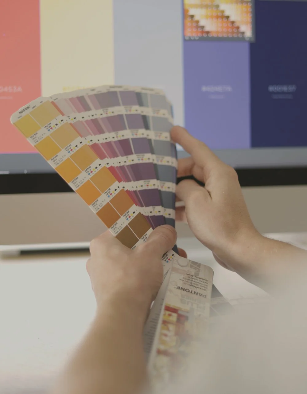 Handen kiezen kleuren uit een kleurenwaaier voor branding en visueel ontwerp