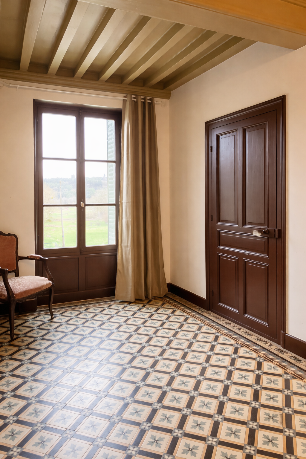 Room with a window, a curtain, a wooden door, a vintage chair, and patterned tile flooring.