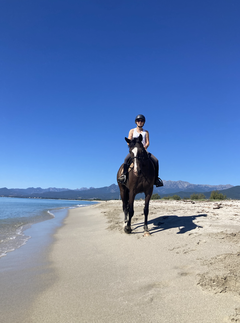 Cavalière lors d’une balade à cheval sur la plage de Calzarellu en Corse