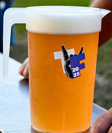 A plastic pour-over beer pitcher filled with beer that has a foamy head.