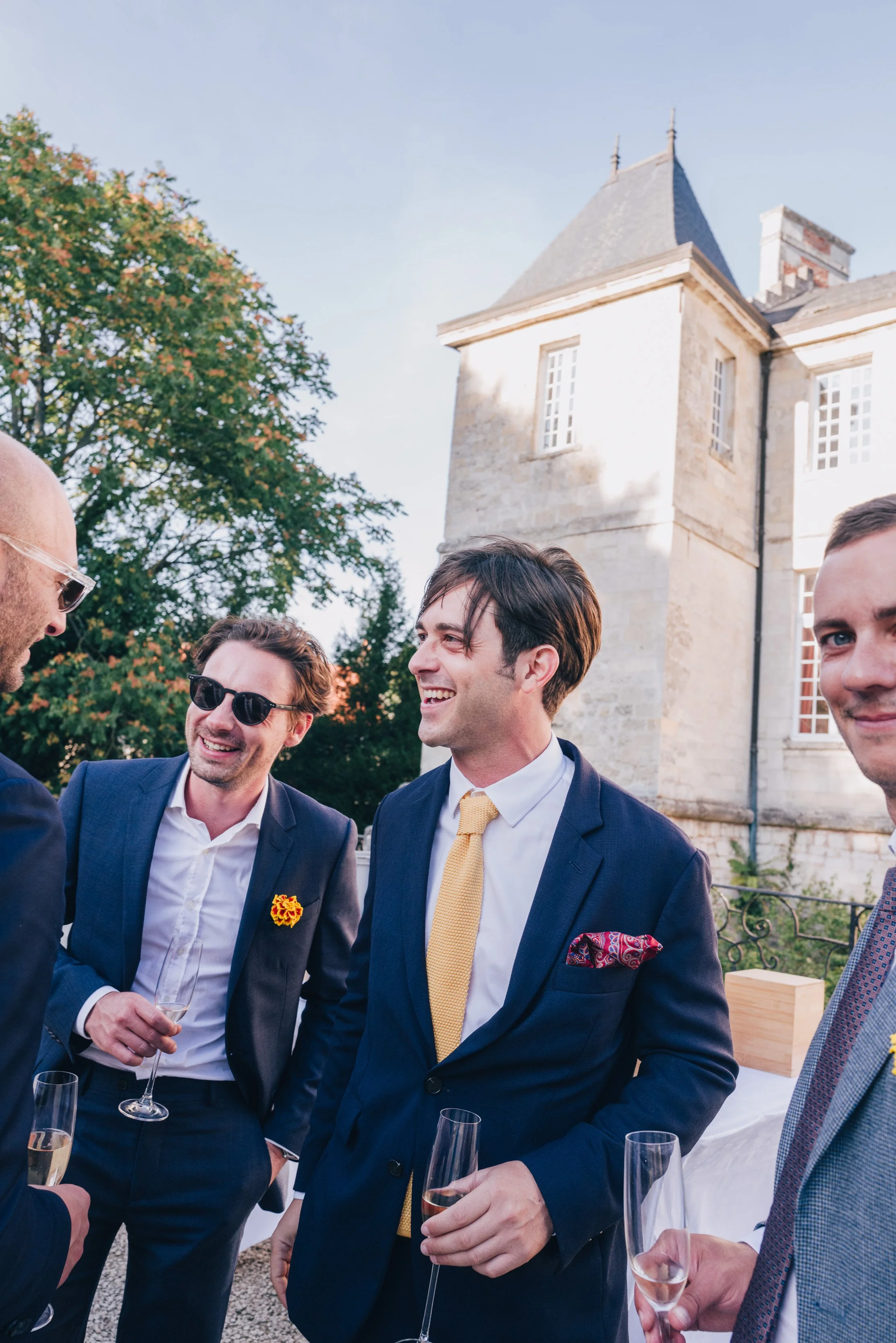 Groupe d'hommes en costume discutant lors d'un mariage