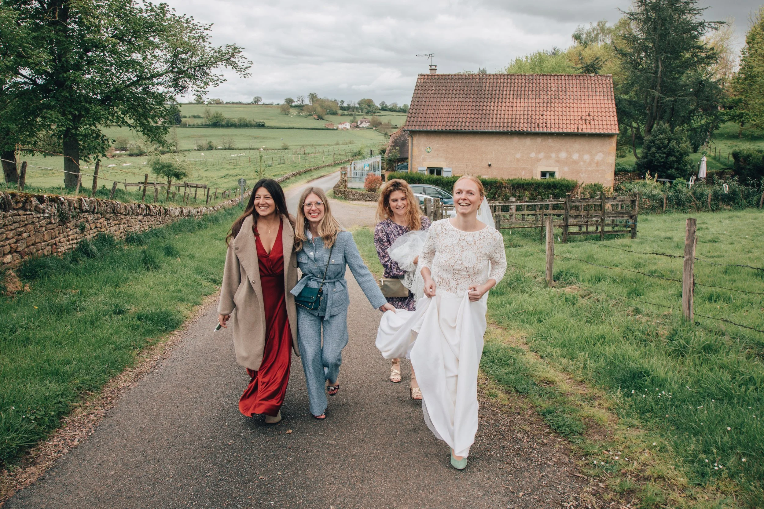 Mariée entourée de ses amies sur un chemin menant à la salle de mariage