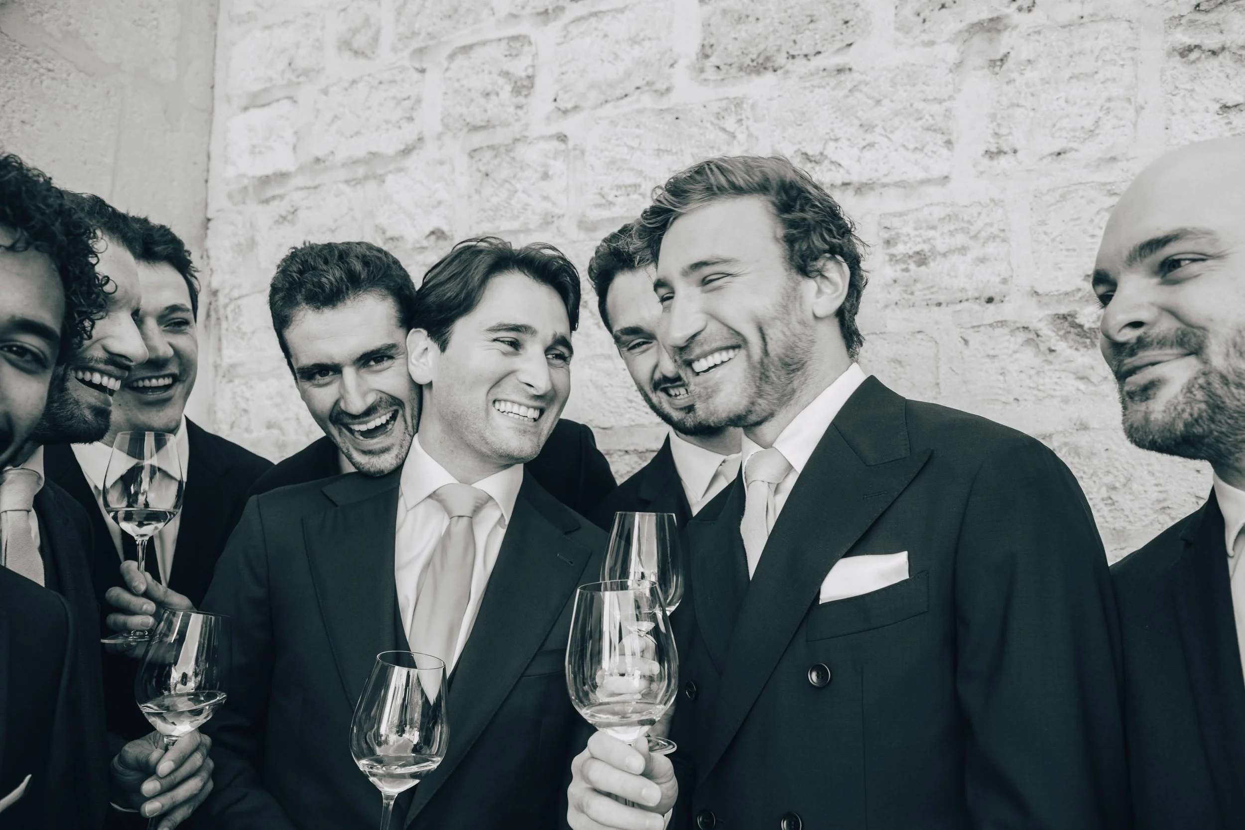 Photographie d'un groupe d'hommes en costume lors d'une réception de mariage