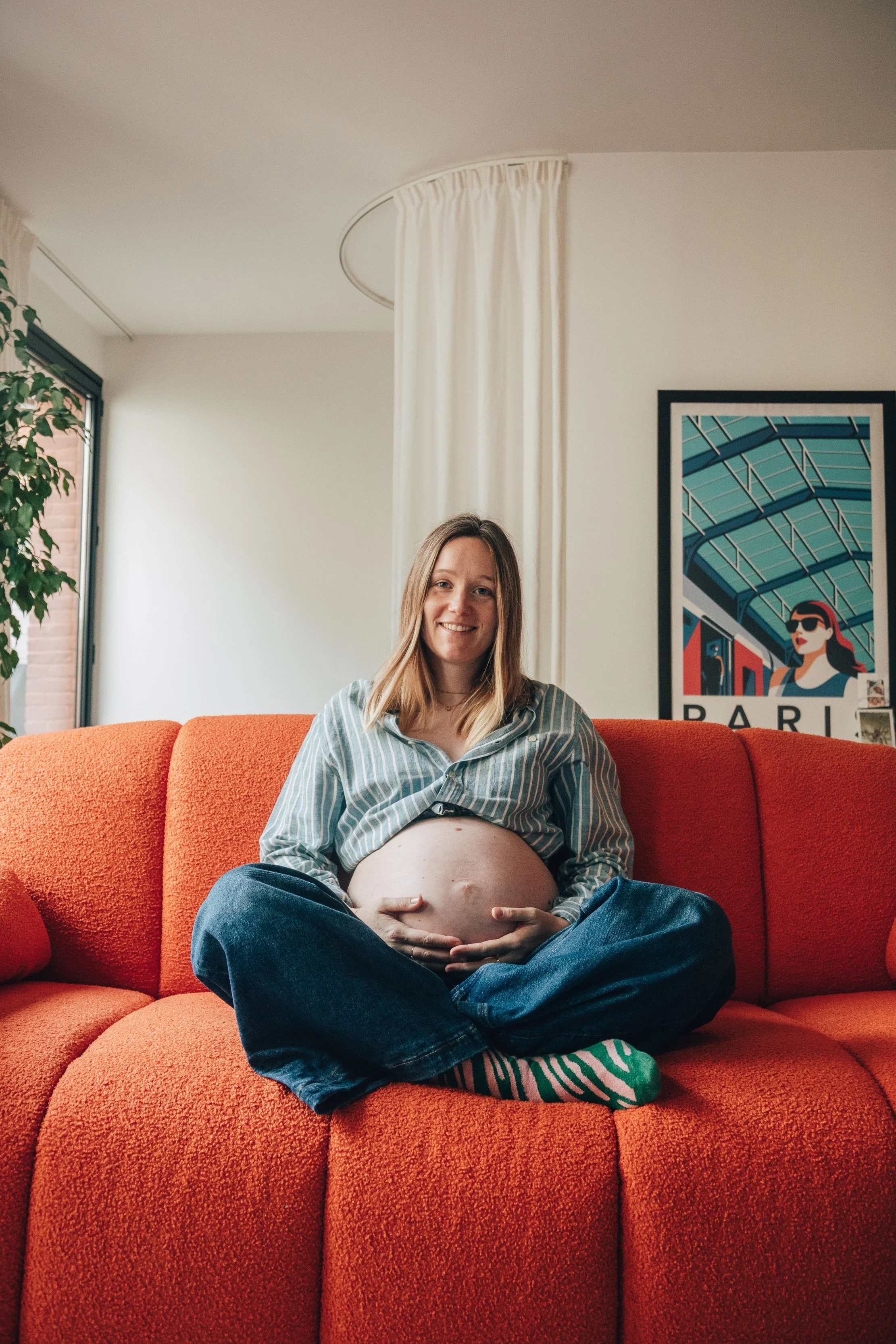 Femme enceinte assise sur un canapé orange