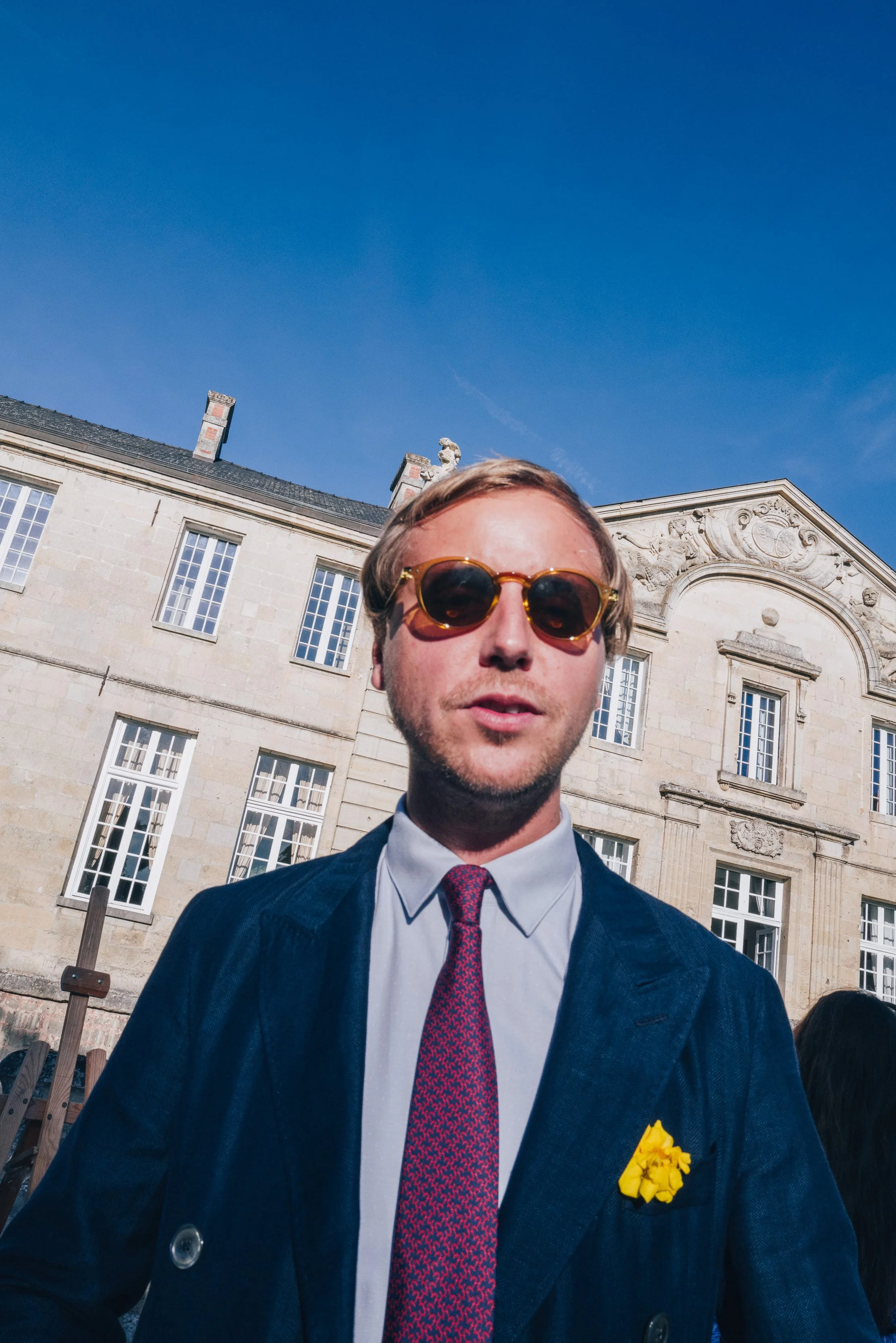 Un homme habillé en costume, portant des lunettes de soleil lors d'un mariage dans un domaine privé