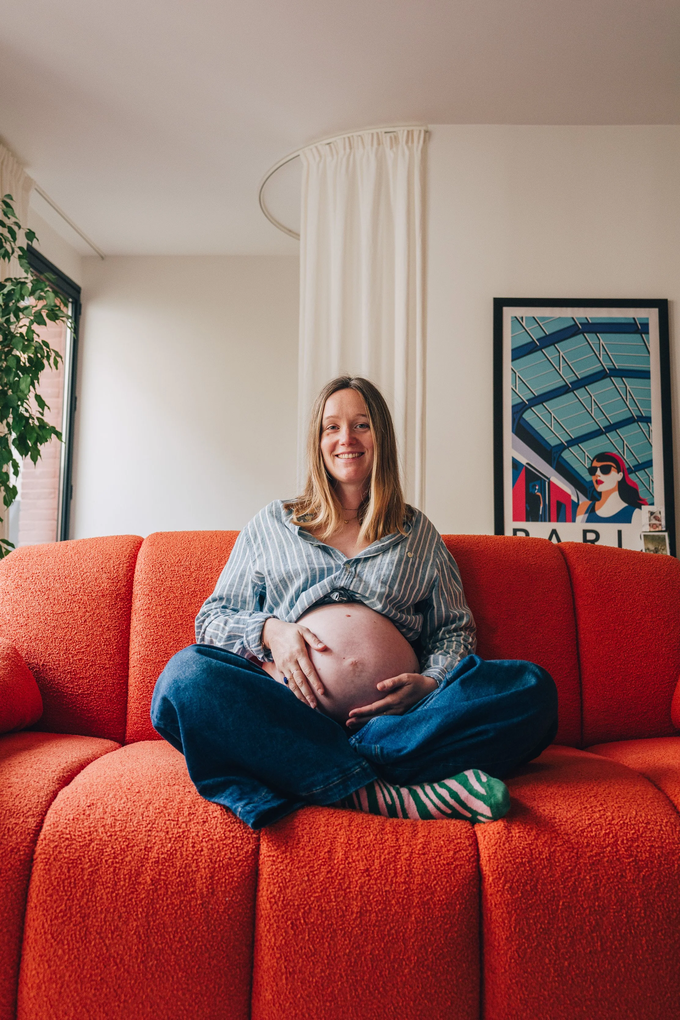 Femme enceinte assise sur un canapé orange