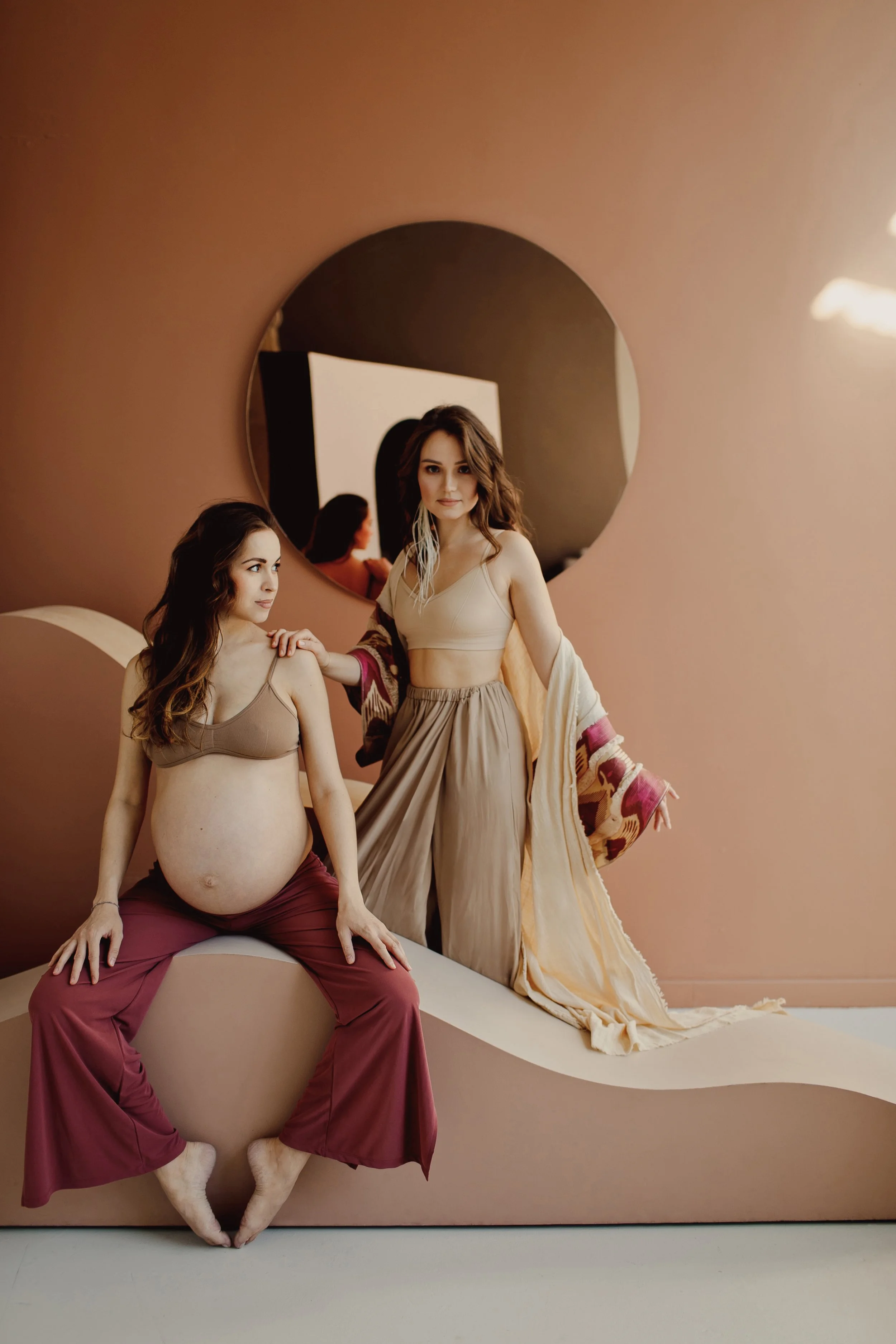 Doula standing beside a pregnant client in a warm-toned studio – contact Bump to Baby in Abu Dhabi
