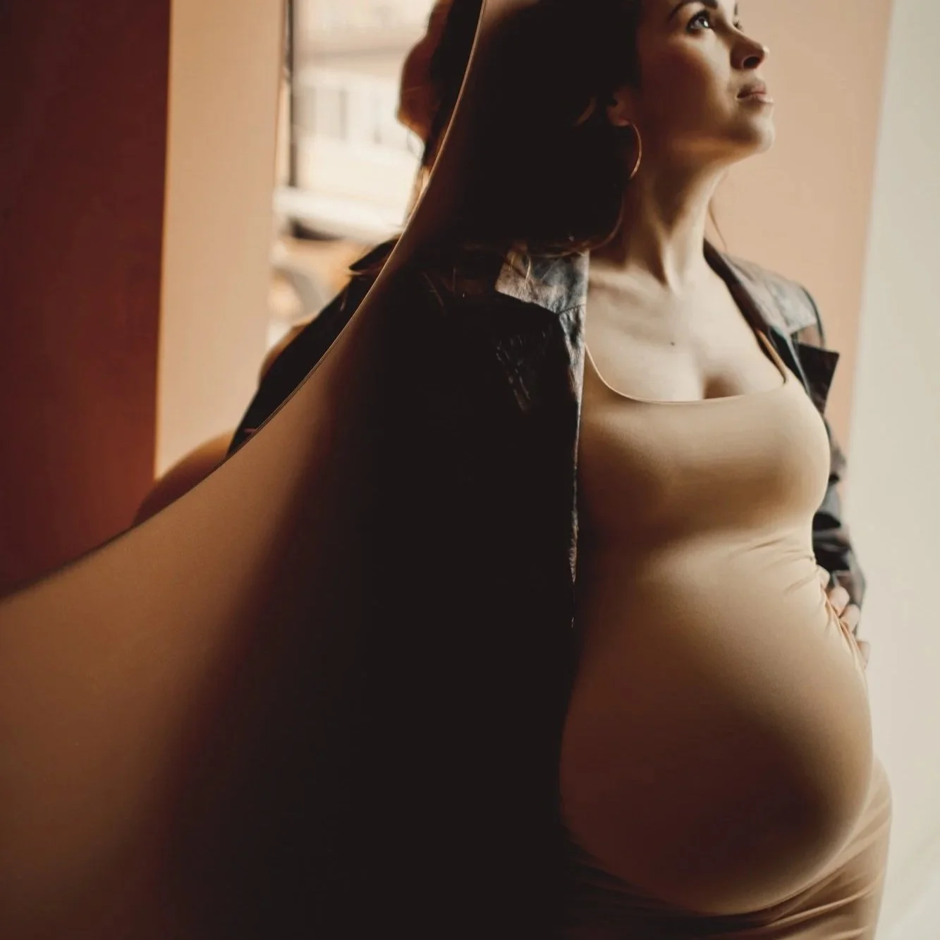 Pregnant woman standing in warm window light – Premium Care doula package