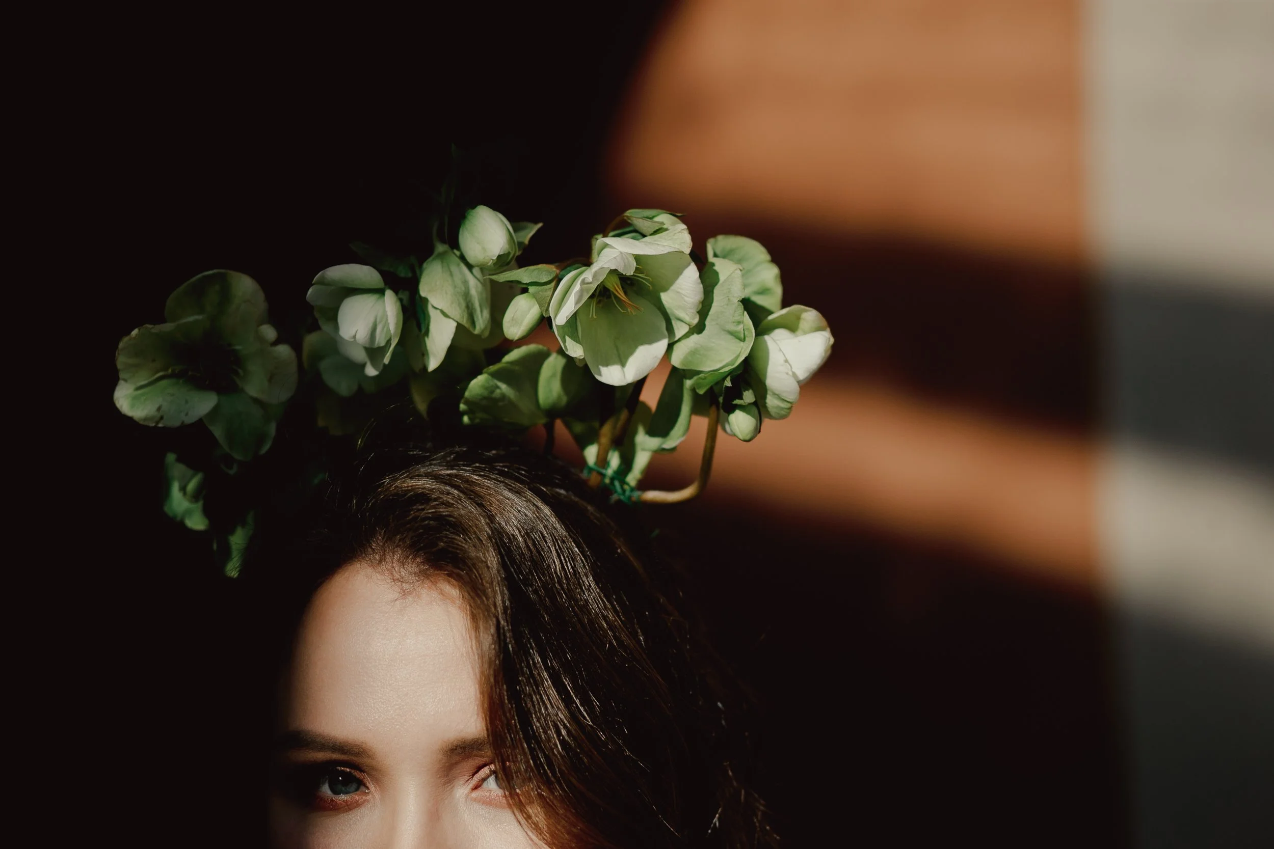 Woman with green leaves above her head in warm, dramatic light