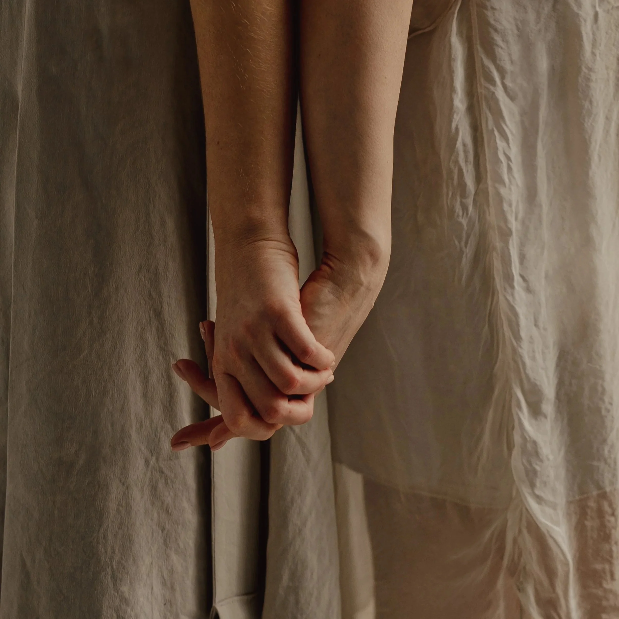 Woman's hands clasped against a linen dress – postpartum home visit