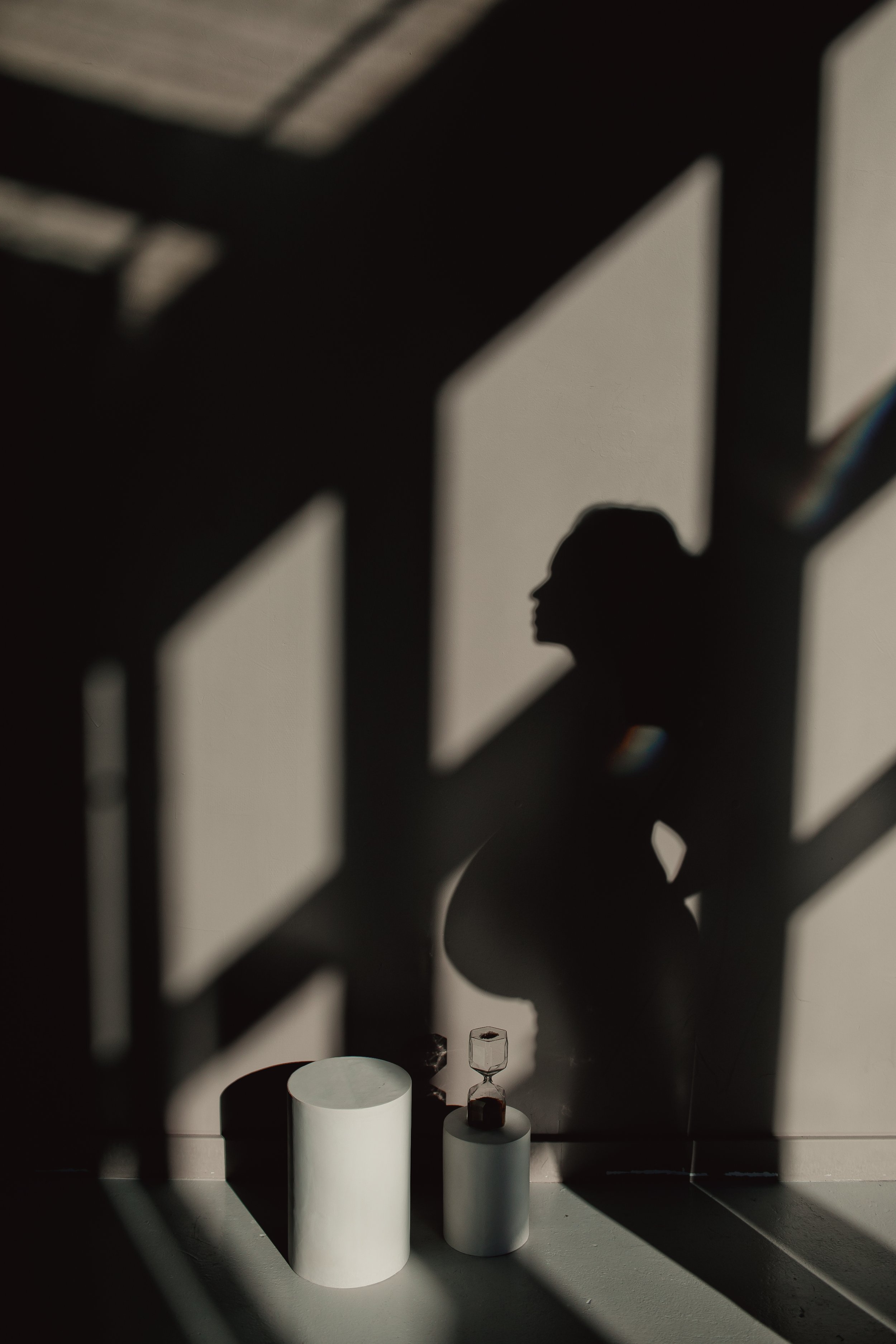 Silhouette of a pregnant woman in window light and shadow