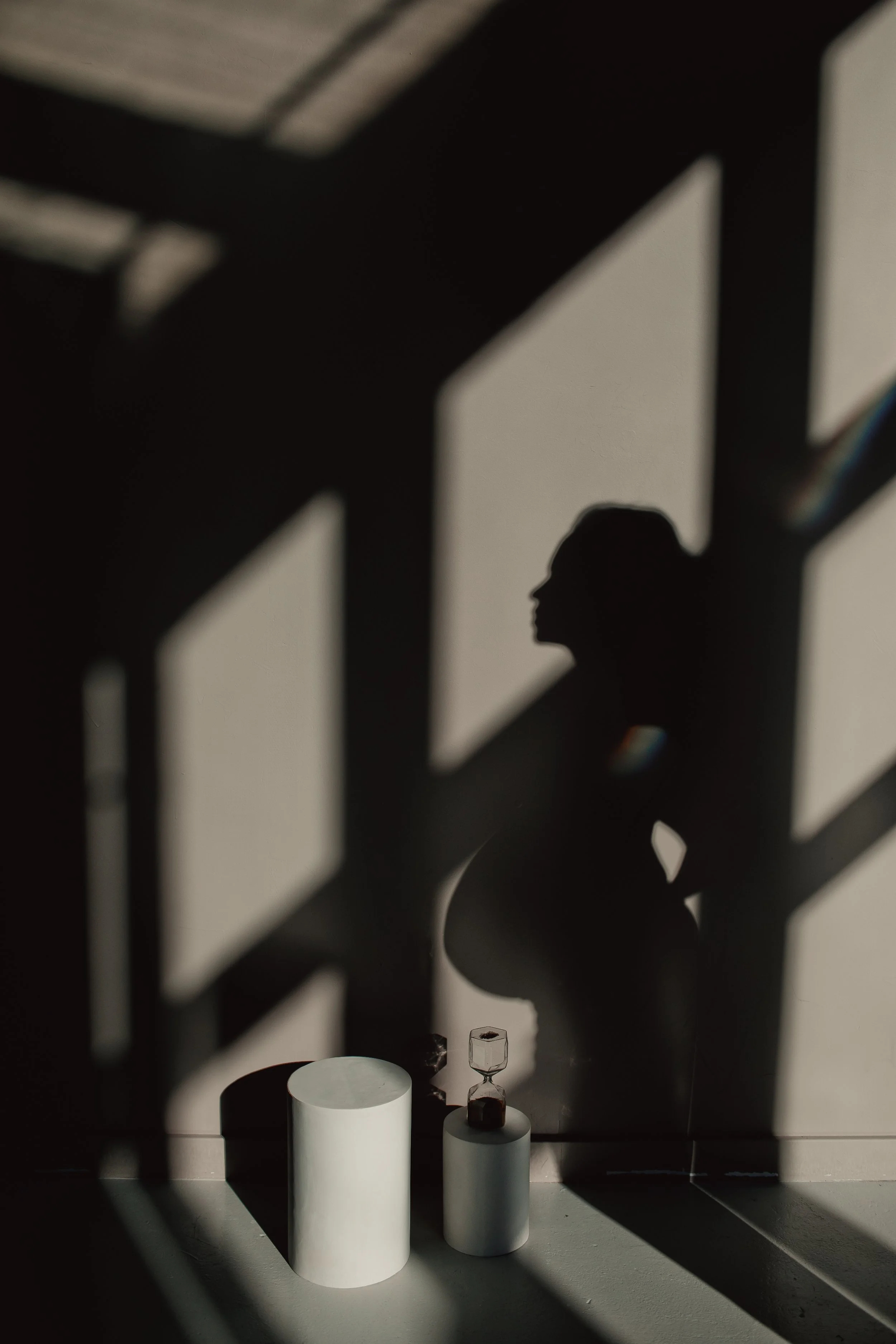 Silhouette of a pregnant woman in window light and shadow