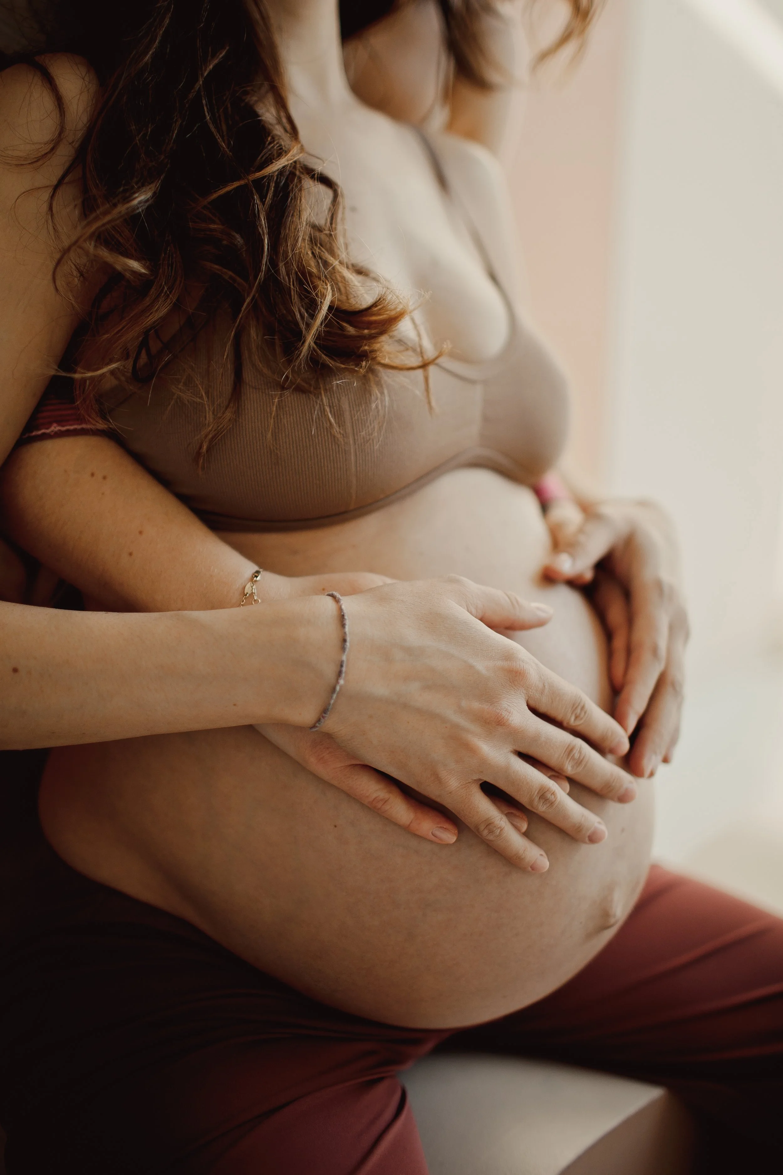 Pregnant woman holding her baby bump with both hands – doula support in Abu Dhabi