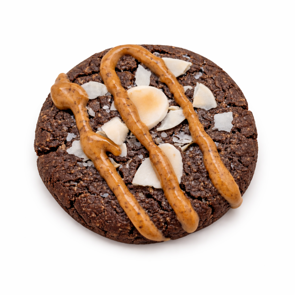 Chocolate cookie topped with white flakes, almond slices, and caramel drizzle.