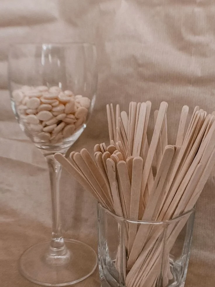 Ein Glas mit weißen Zuckerstangen, ein Glas voller Holz-Picks für Essen, auf einem Holz Tisch.