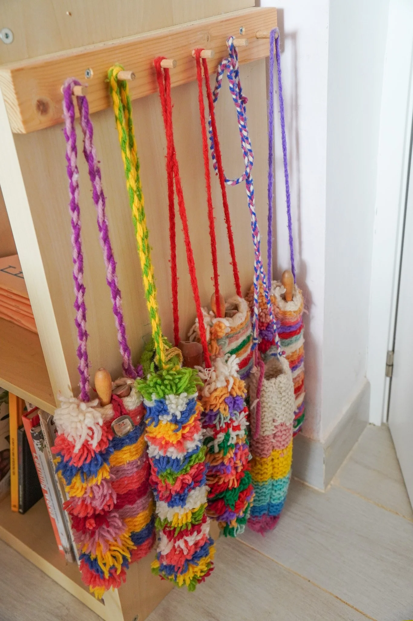 Colgadores de madera con guantes de lana multicolores en un mueble de madera.