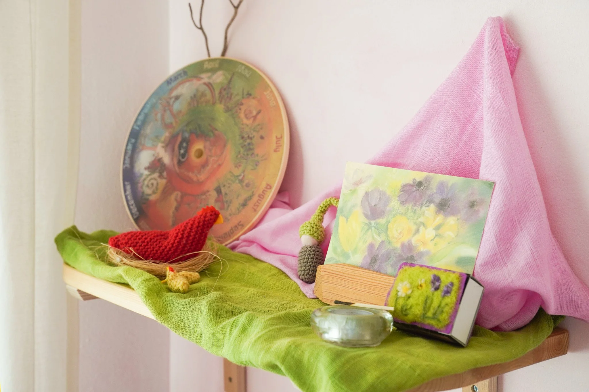 Puente astronómico con colores del arcoíris y elementos decorativos de colores, con una mesa cubierta con tela rosa y verde, y varias piezas artísticas y objetos decorativos sobre ella.