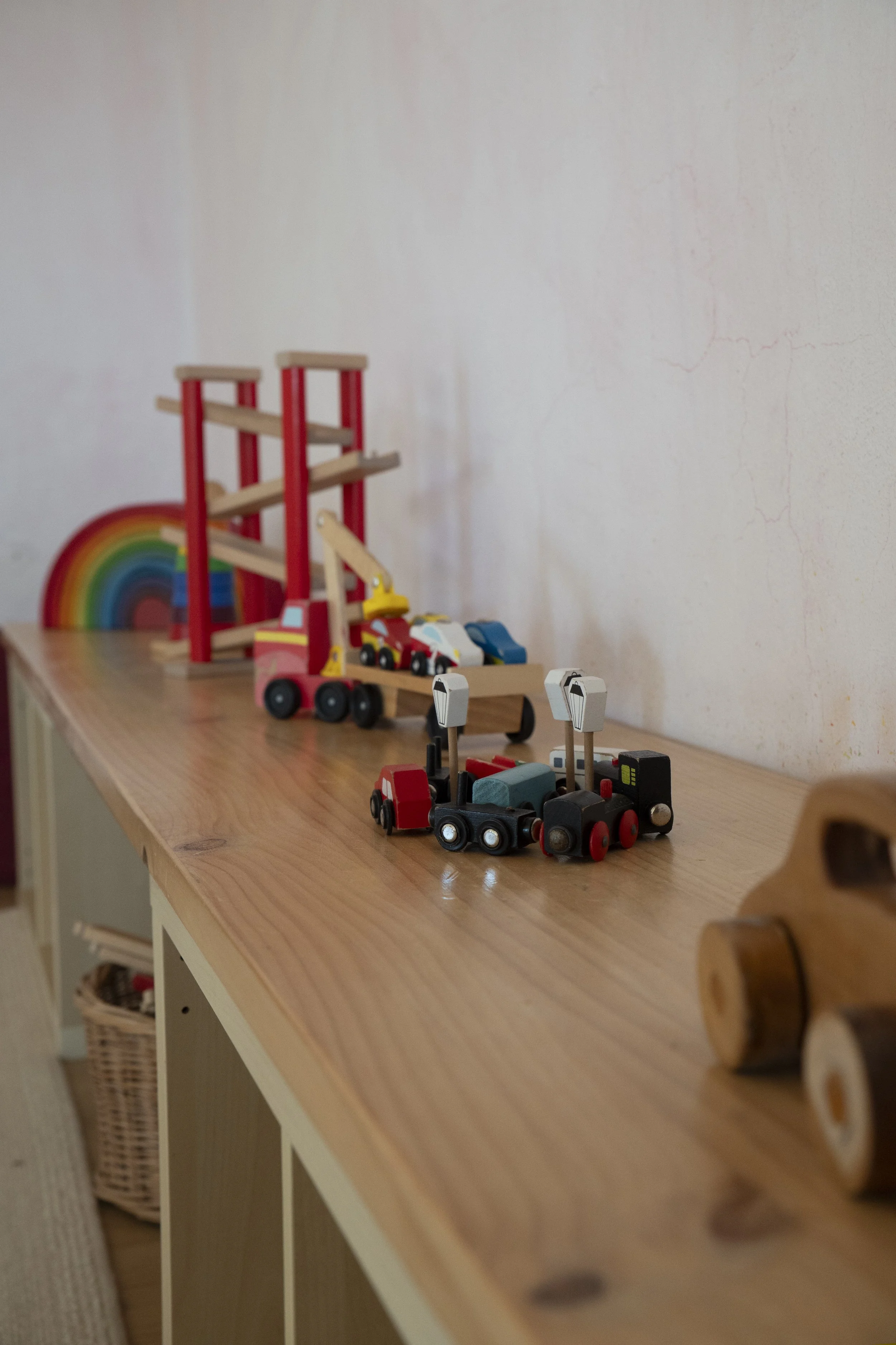 Juguetes de madera en una repisa de madera: arcoiris, escaleras, autos y trenes.