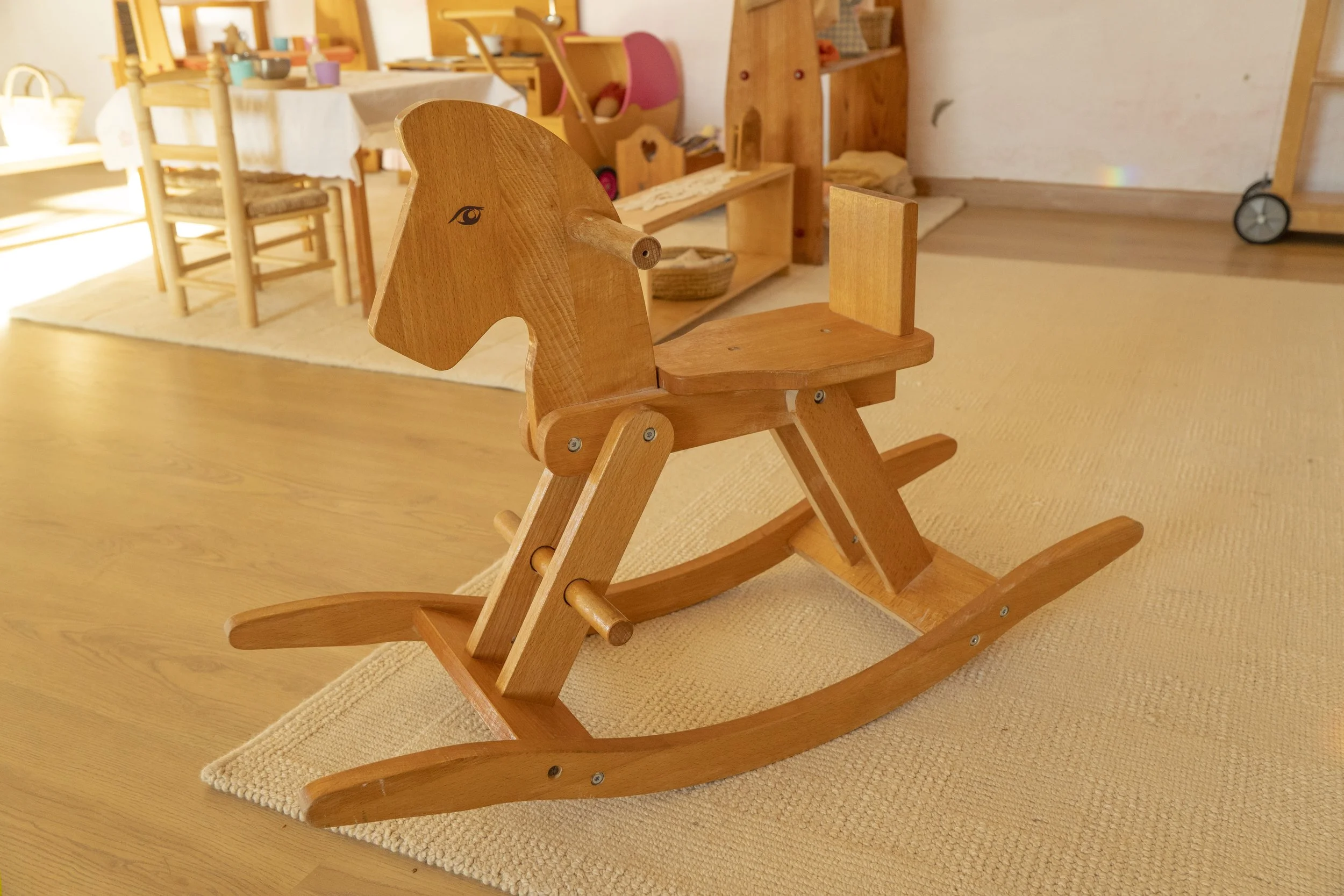 Silla de madera en forma de caballo en un ambiente infantil con muebles de madera y decoración en tonos cálidos.