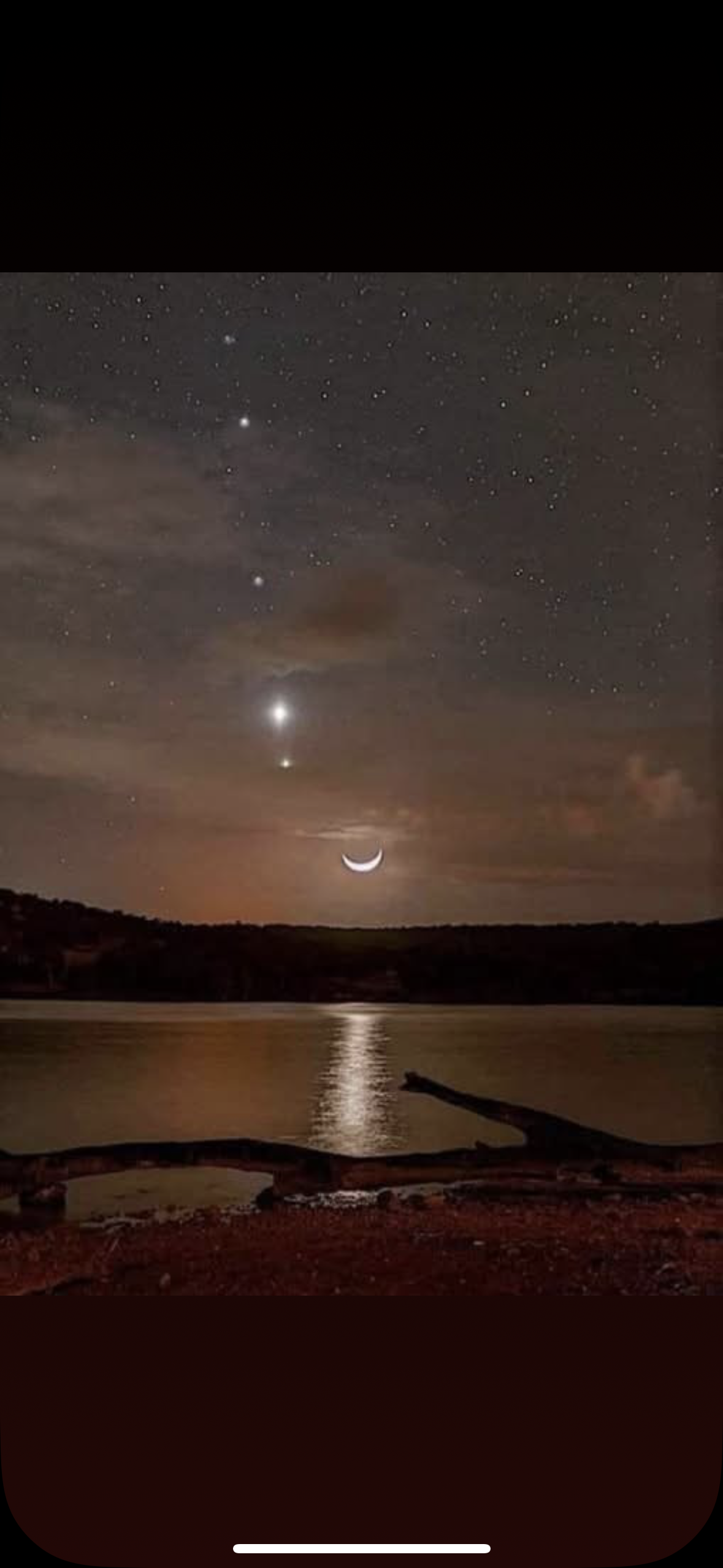 Nattlandskap med stjärnor, en halvmåne och en reflektion i vattnet, med berg i bakgrunden.