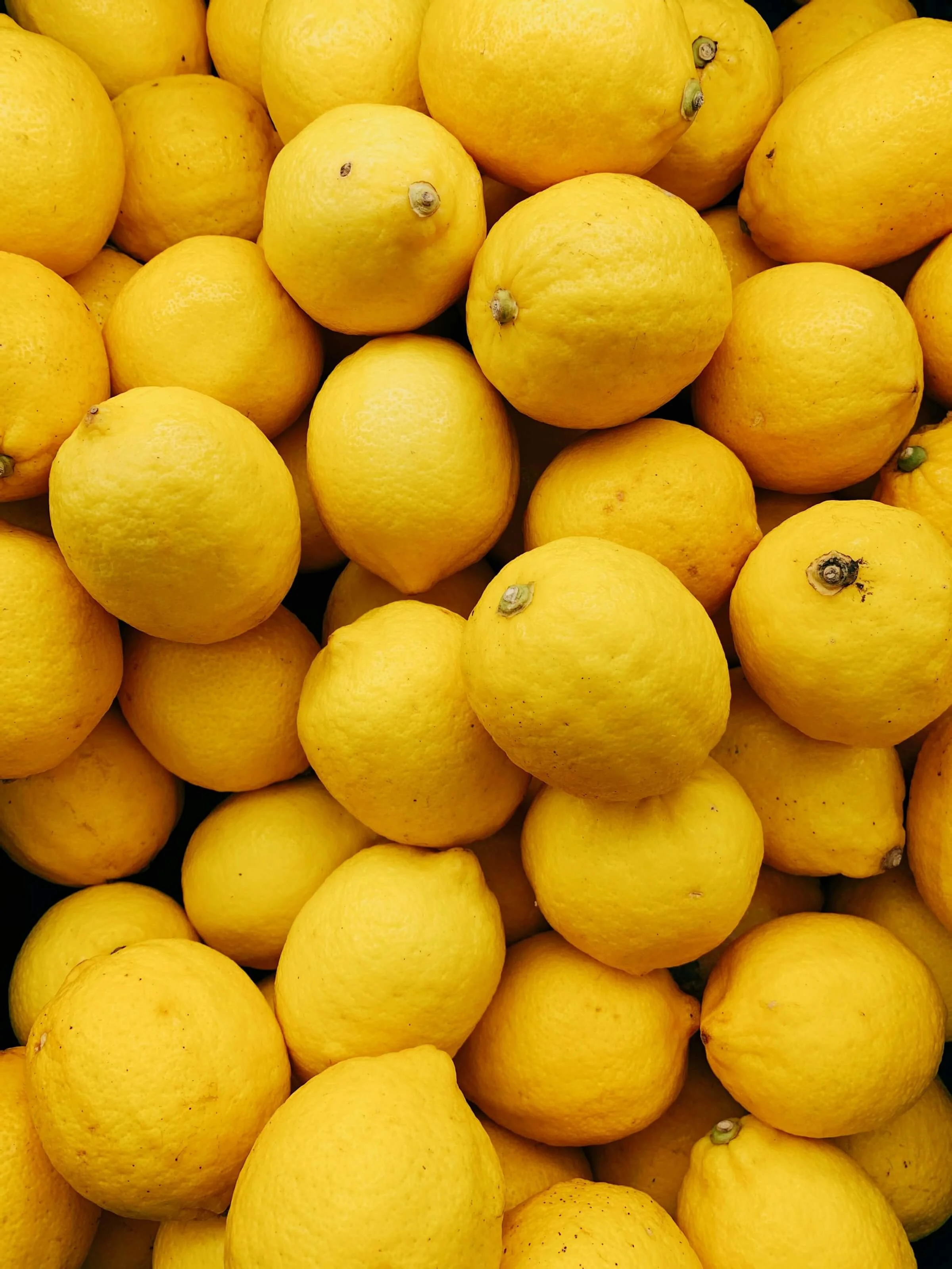 A pile of bright yellow lemons arranged together.