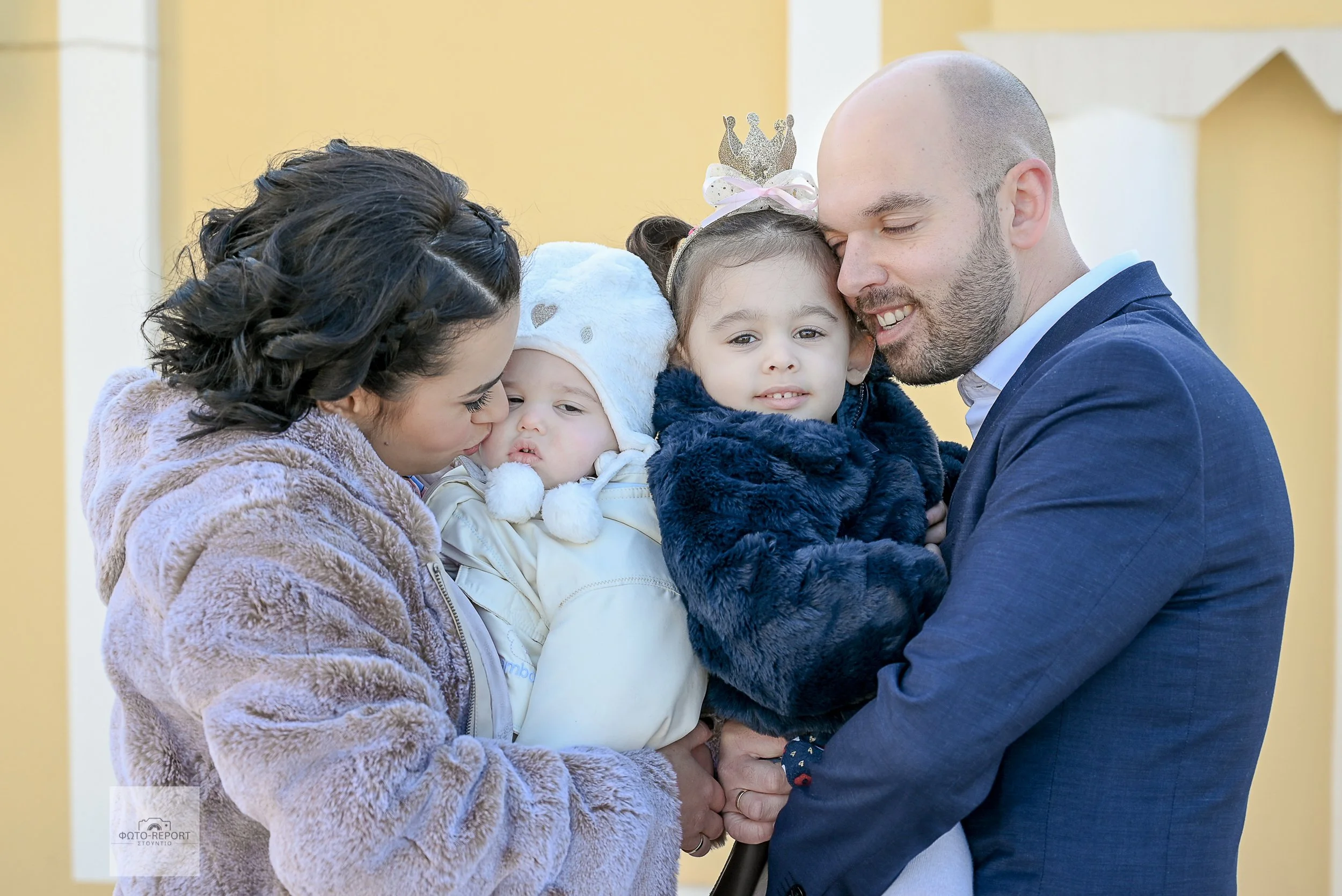 Τρυφερή οικογενειακή αγκαλιά με τους γονείς και τα δύο τους παιδιά. Αυθόρμητα πορτρέτα και φωτογράφιση βάπτισης (Αθήνα).