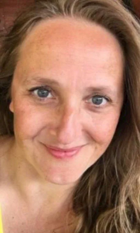 Nærbillede af en smilende kvindes ansigt med langt, lyst hår og blå øjne