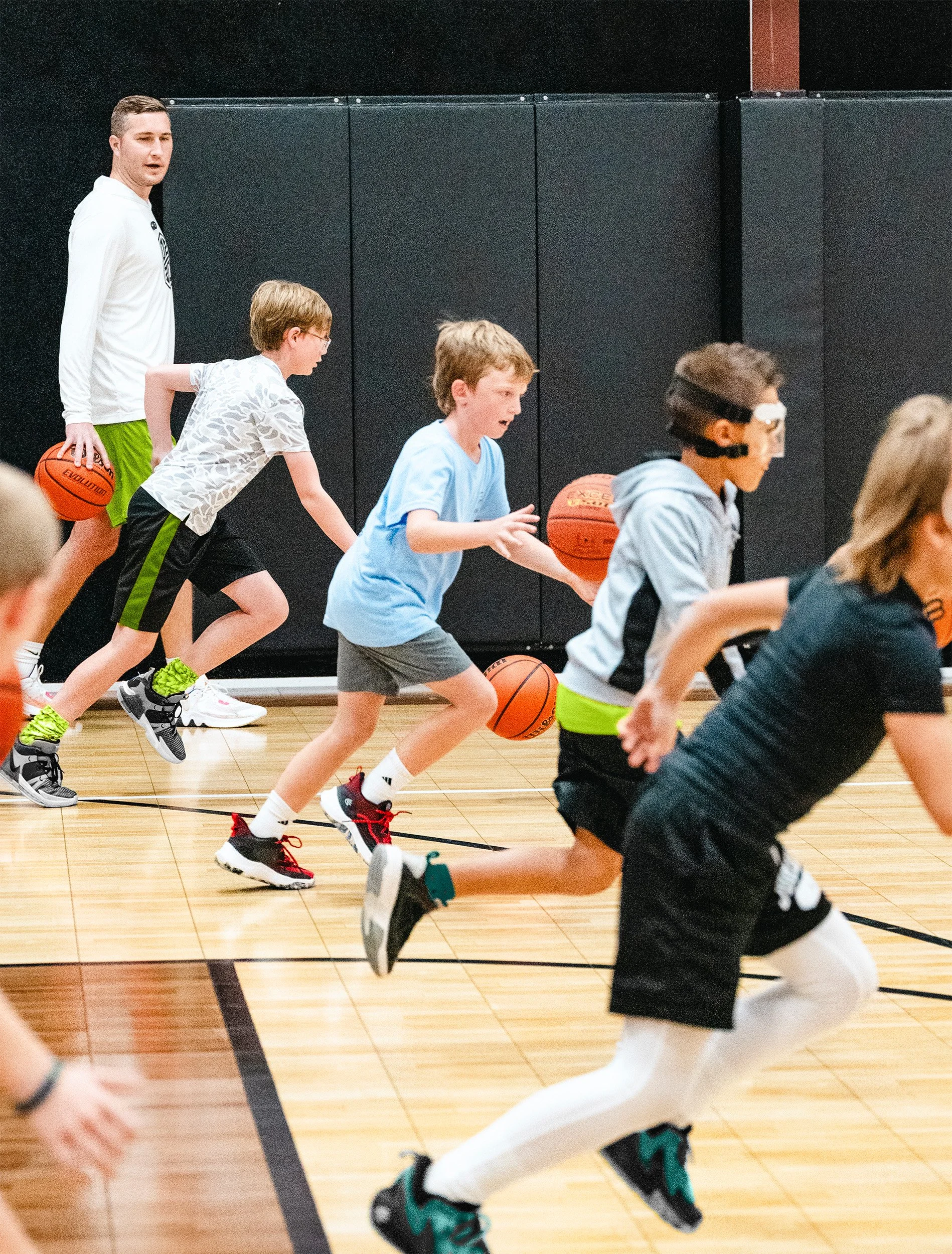 Youth basketball academy players running competitive drill at indoor clinic in Dripping Springs, TX