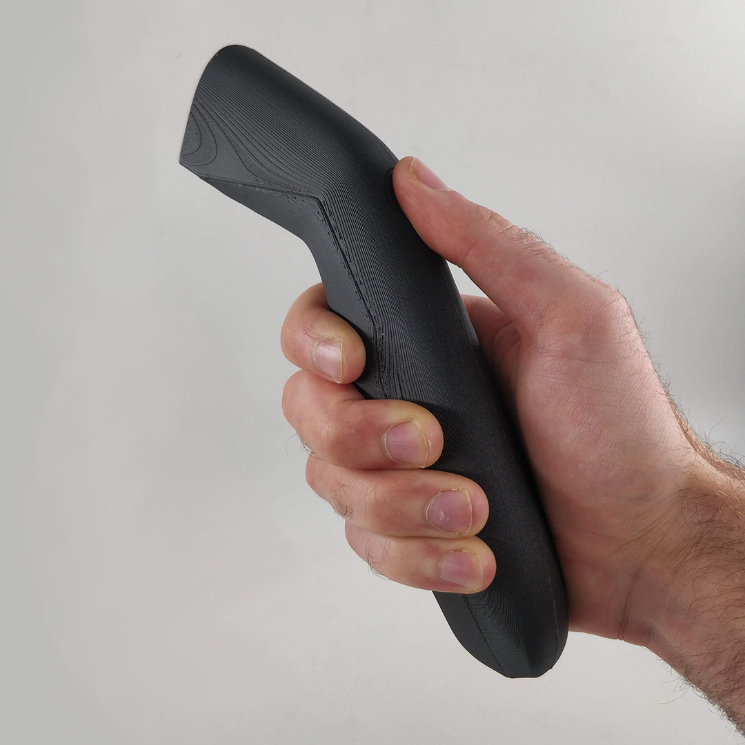 Hand holding a black 3D-printed gun shape object against a plain white background.