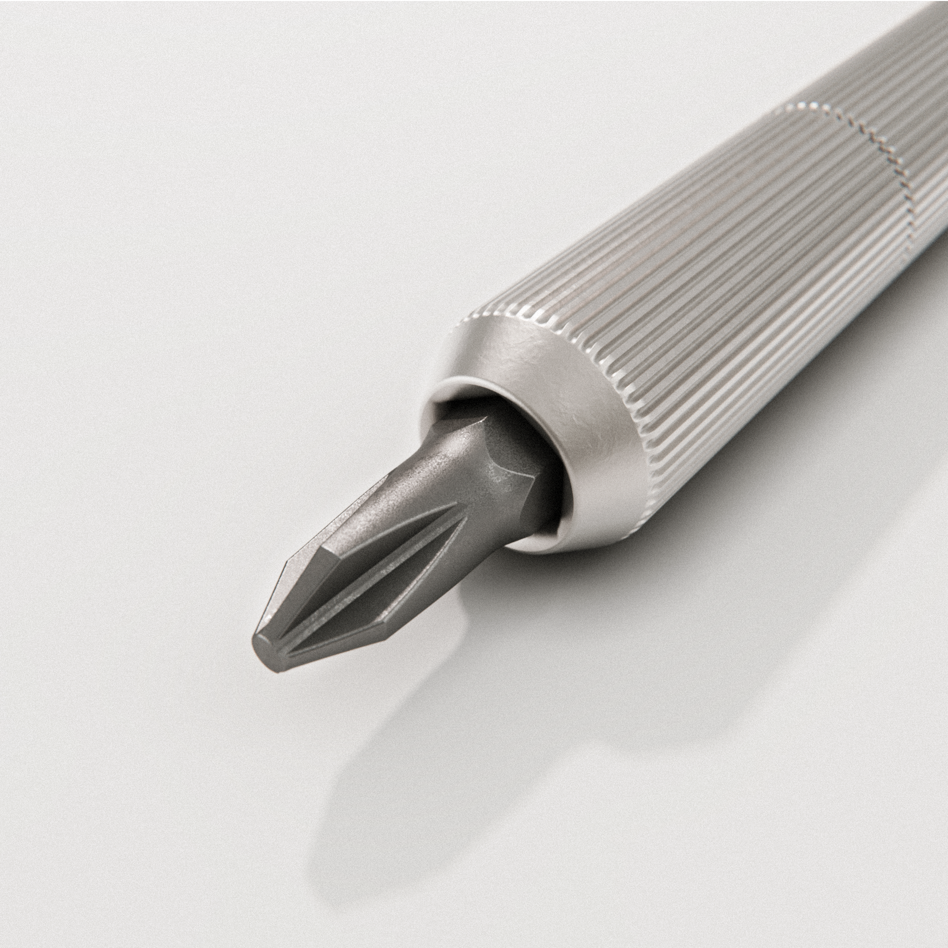 Close-up of a precision screwdriver with a knurled metallic handle and flat-head tip on a light background.