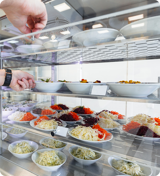 refrigerated display case with bowls of shredded vegetables and toppings including cabbage, carrots, and beets.