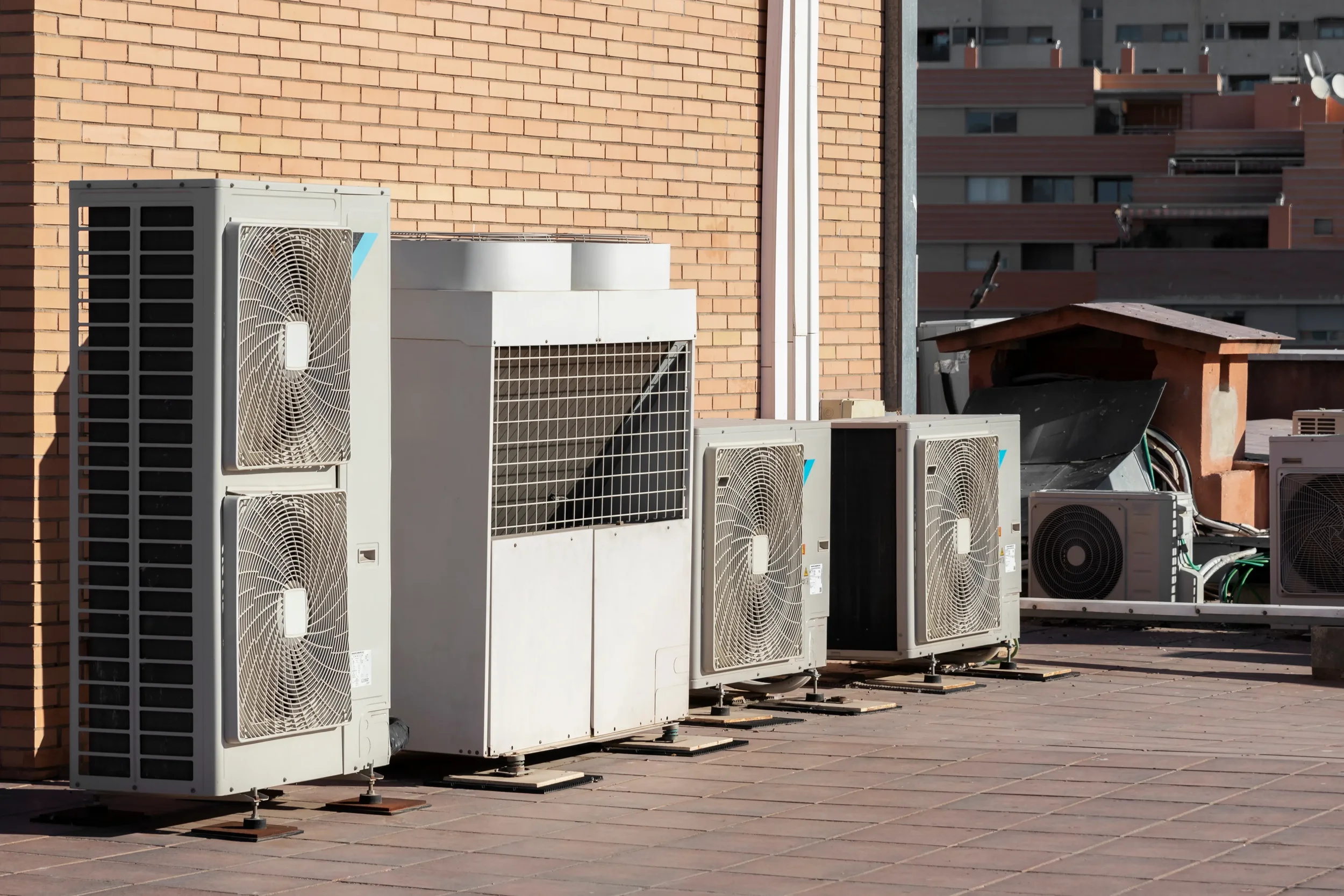 Various HVAC units installed on a rooftop next to a brick wall.