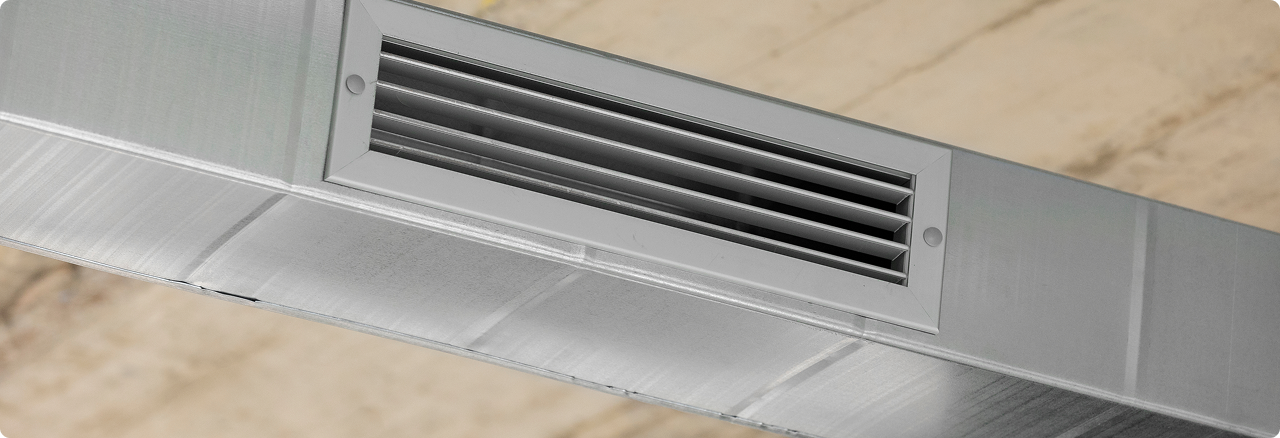 Close-up of a ceiling air vent on a metallic surface.