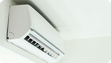 Wall-mounted white air conditioner with adjustable vent louvers in a room with white ceiling
