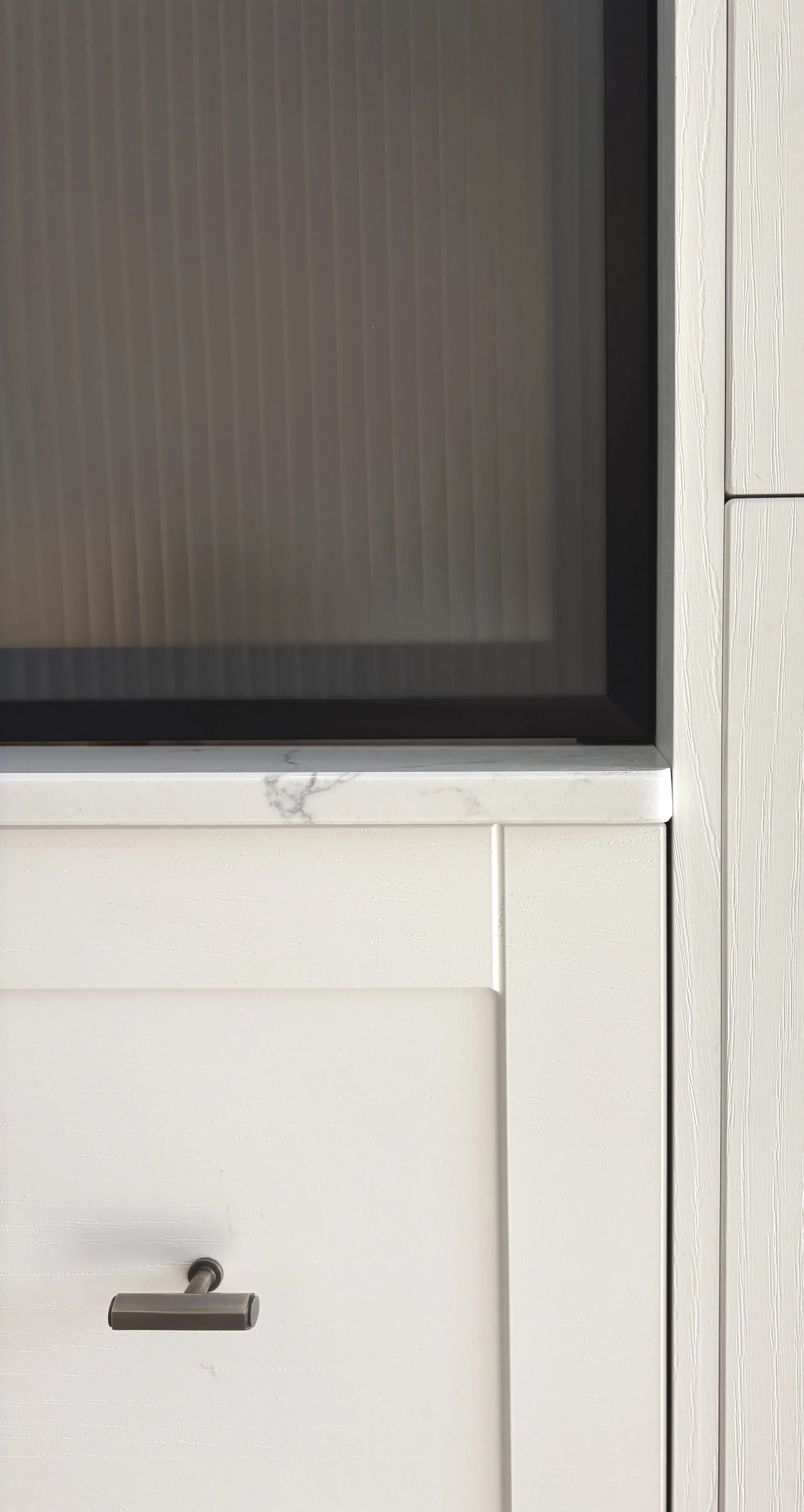 Close-up of a microwave oven's lower section and surrounding cabinetry, featuring a white drawer with a silver handle, and a countertop with a marble-like pattern.