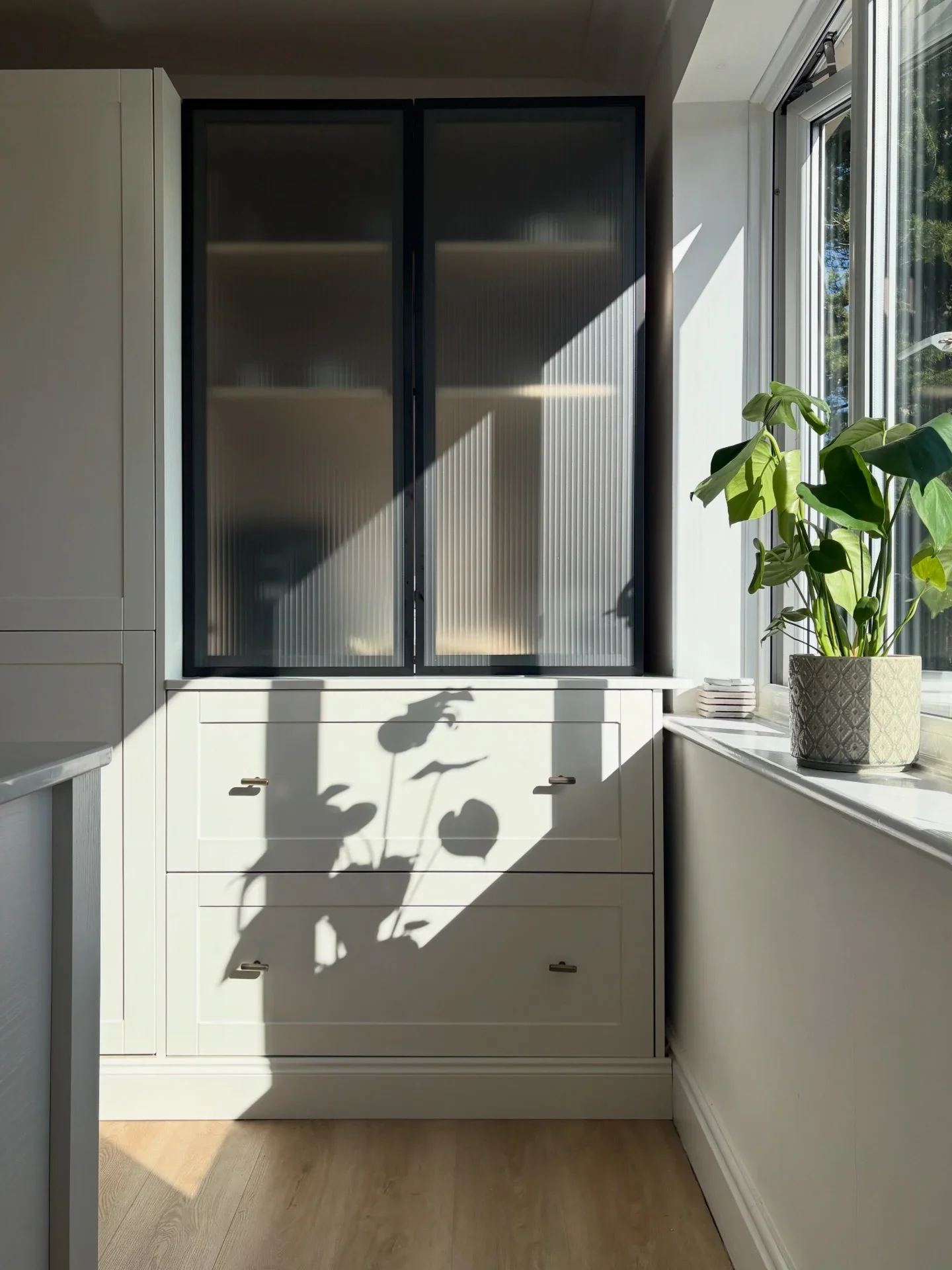 Contemporary kitchen cabinetry featuring fluted glass pantry doors, bespoke shaker joinery, integrated storage and natural light, creating a clean and elegant modern kitchen interior.