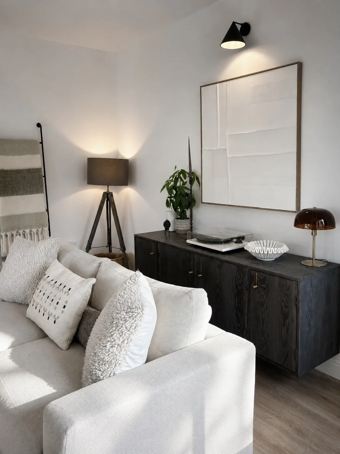 luxury living room corner with white sofa, decorative pillows, black sideboard with decorative items, floor lamp, table lamp, and linen wall art. Modern Interiors.