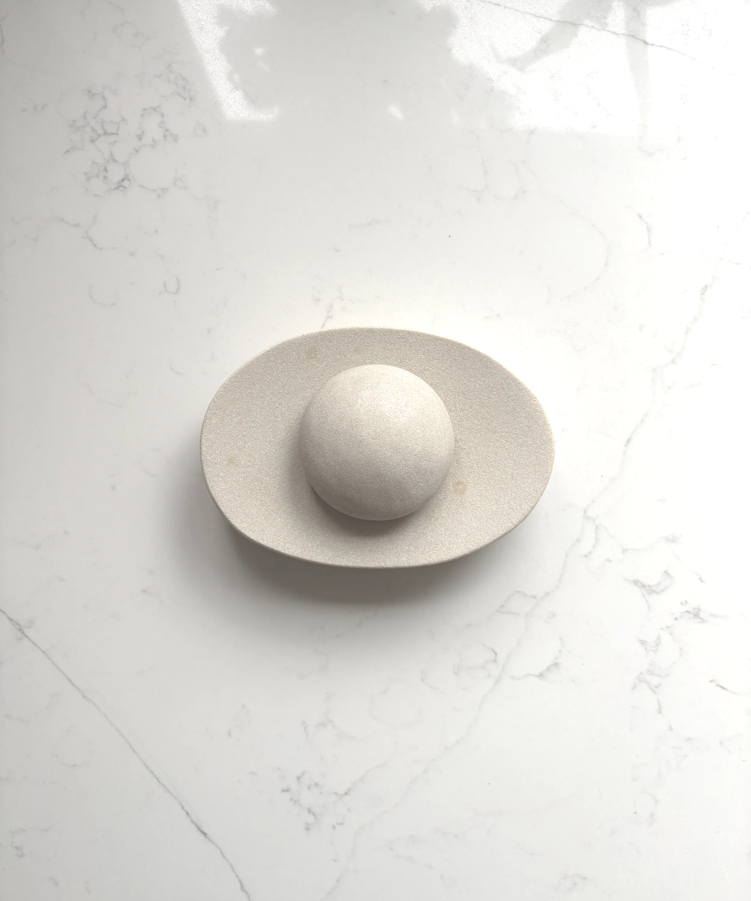 A sculptural white decorative object styled on a marble surface, showcasing refined minimalism, organic forms and contemporary luxury interior design.