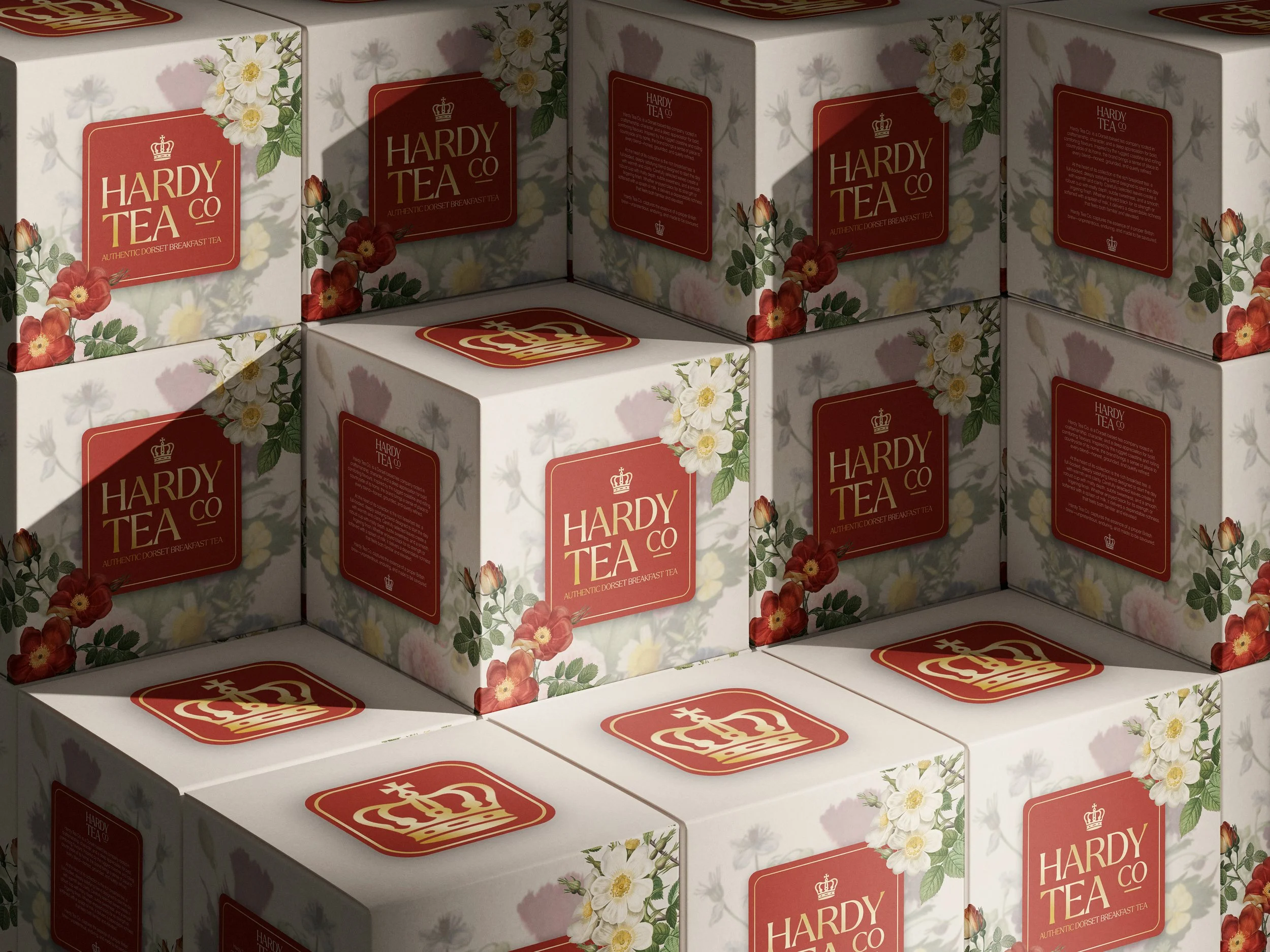 A stack of boxes labeled 'Hardy Tea Co' with floral designs and a red crown logo, arranged to form a pyramid.