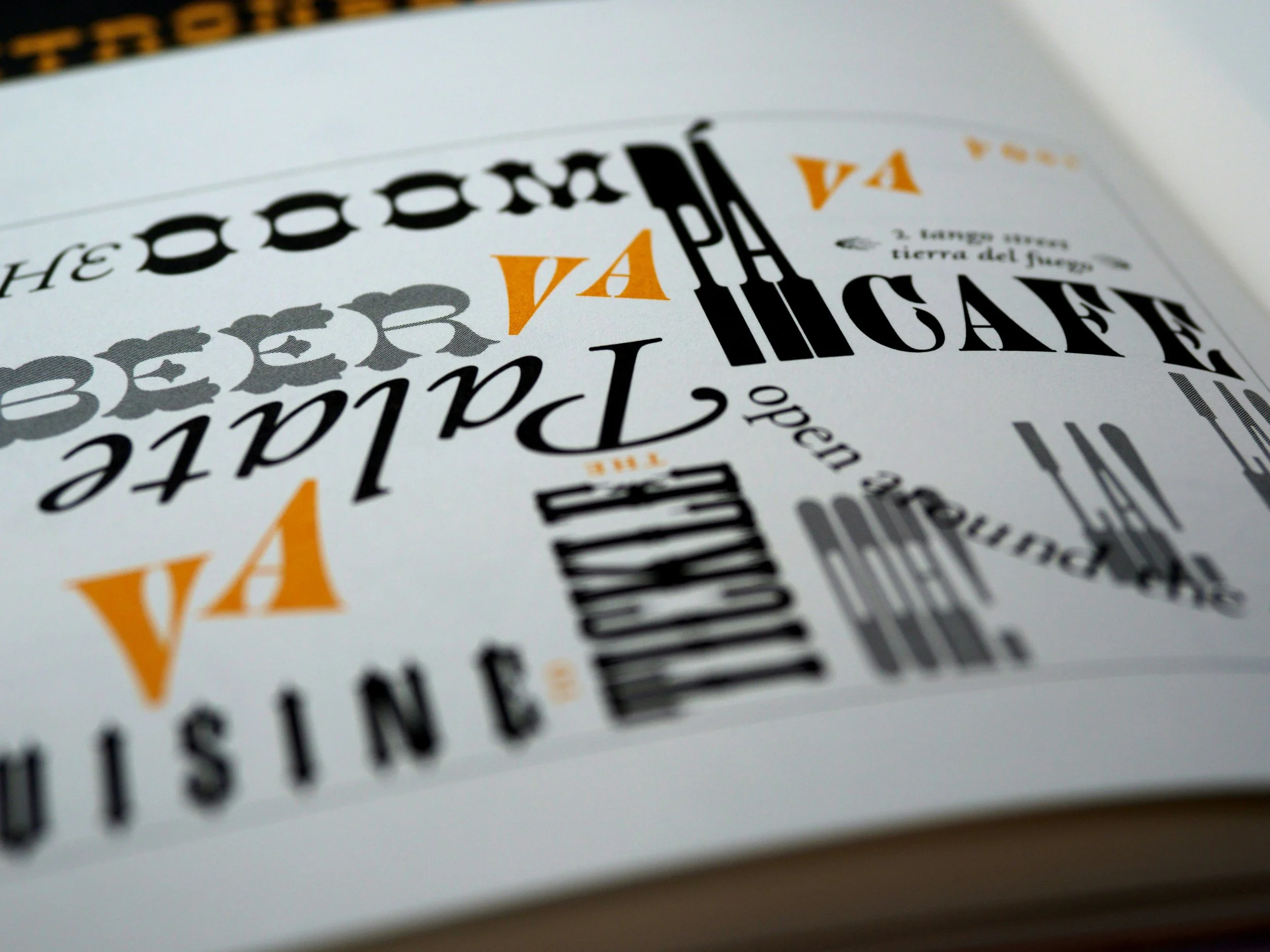 Close-up of a printed card with black and orange text, featuring a stylized design with overlapping letters and numbers.