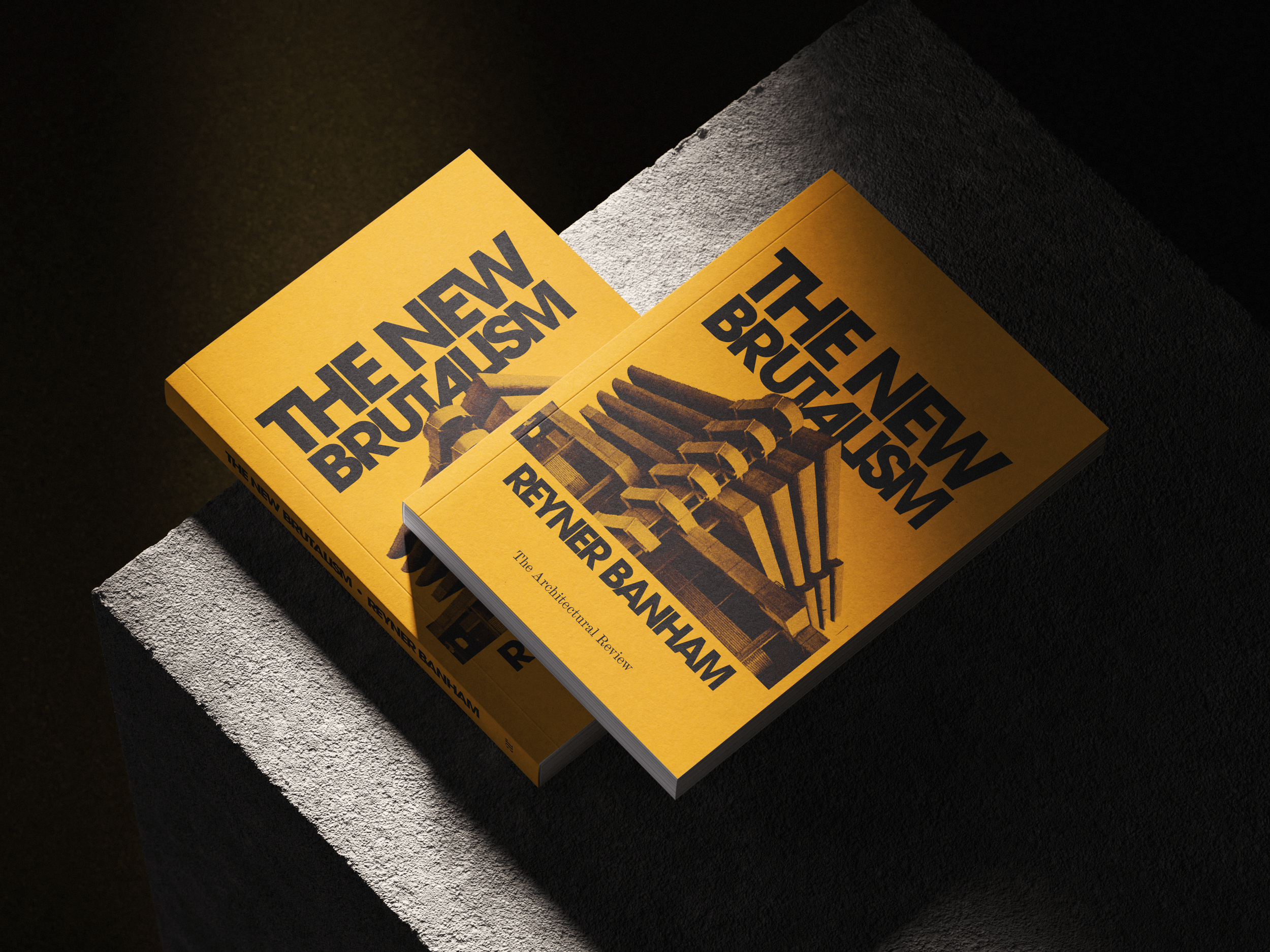 Two yellow books titled "The New Brutalism" by Remner Banham, featuring an architecture-related image on the cover, placed on a dark textured surface.