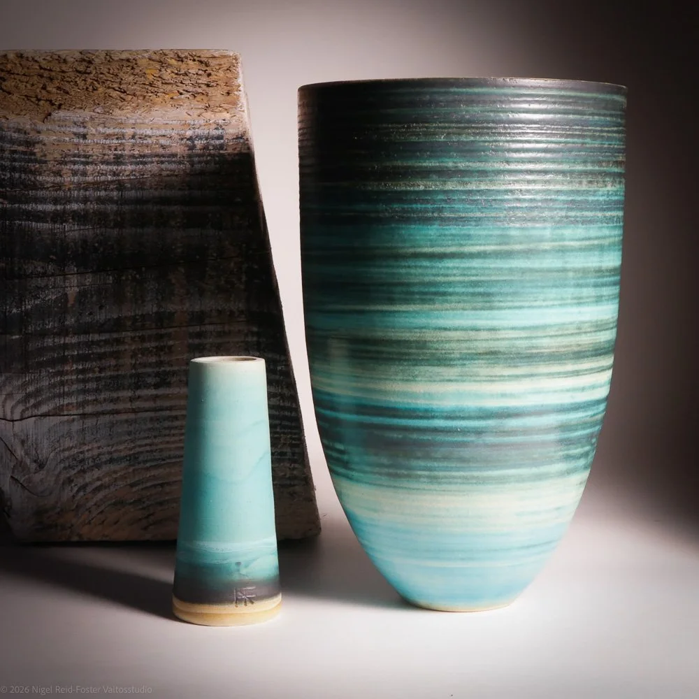 Three ceramic vases of different sizes and colors with a textured, dark background.