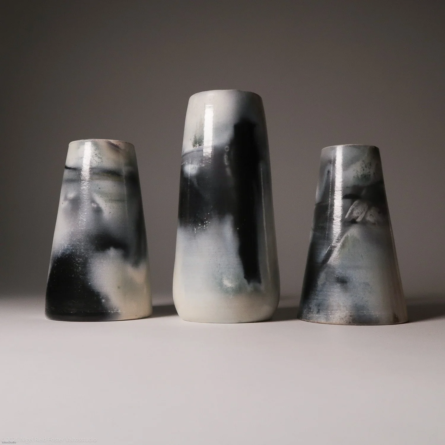 Three black, white, and gray marble-patterned ceramic vases placed on a flat surface against a plain background.
