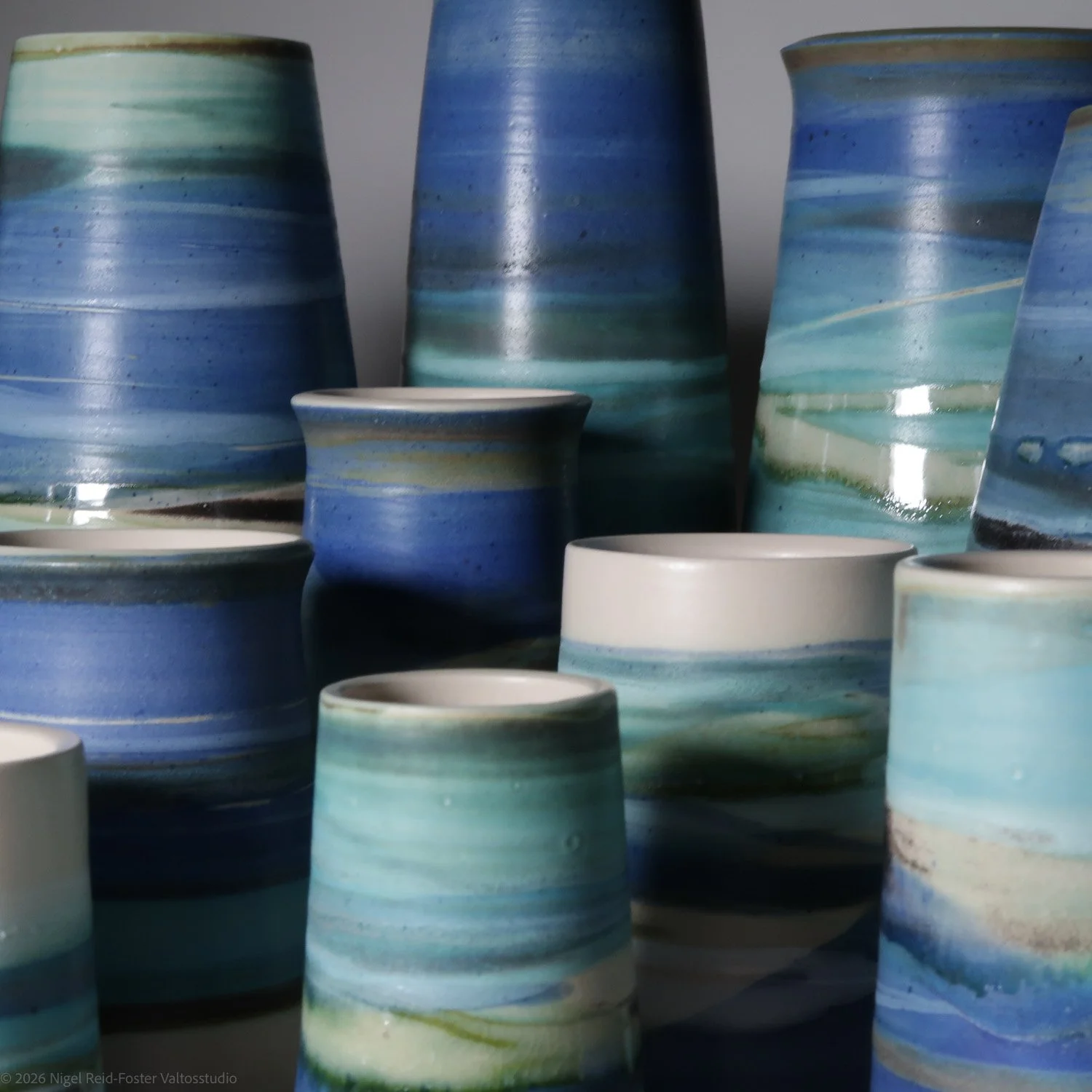 Group of ceramic vases with blue, green, and white glaze in various shapes and sizes.